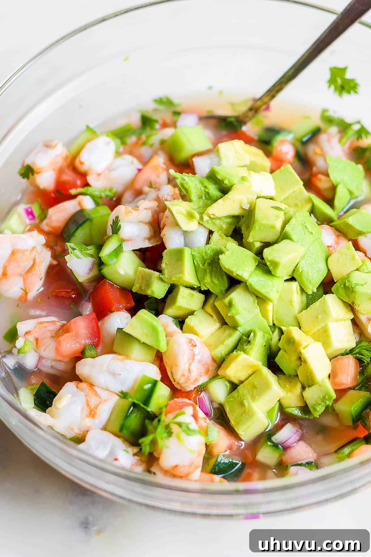 Ceviche The Zesty Seafood Sensation 8 Avocado being mixed into a bowl of ceviche.