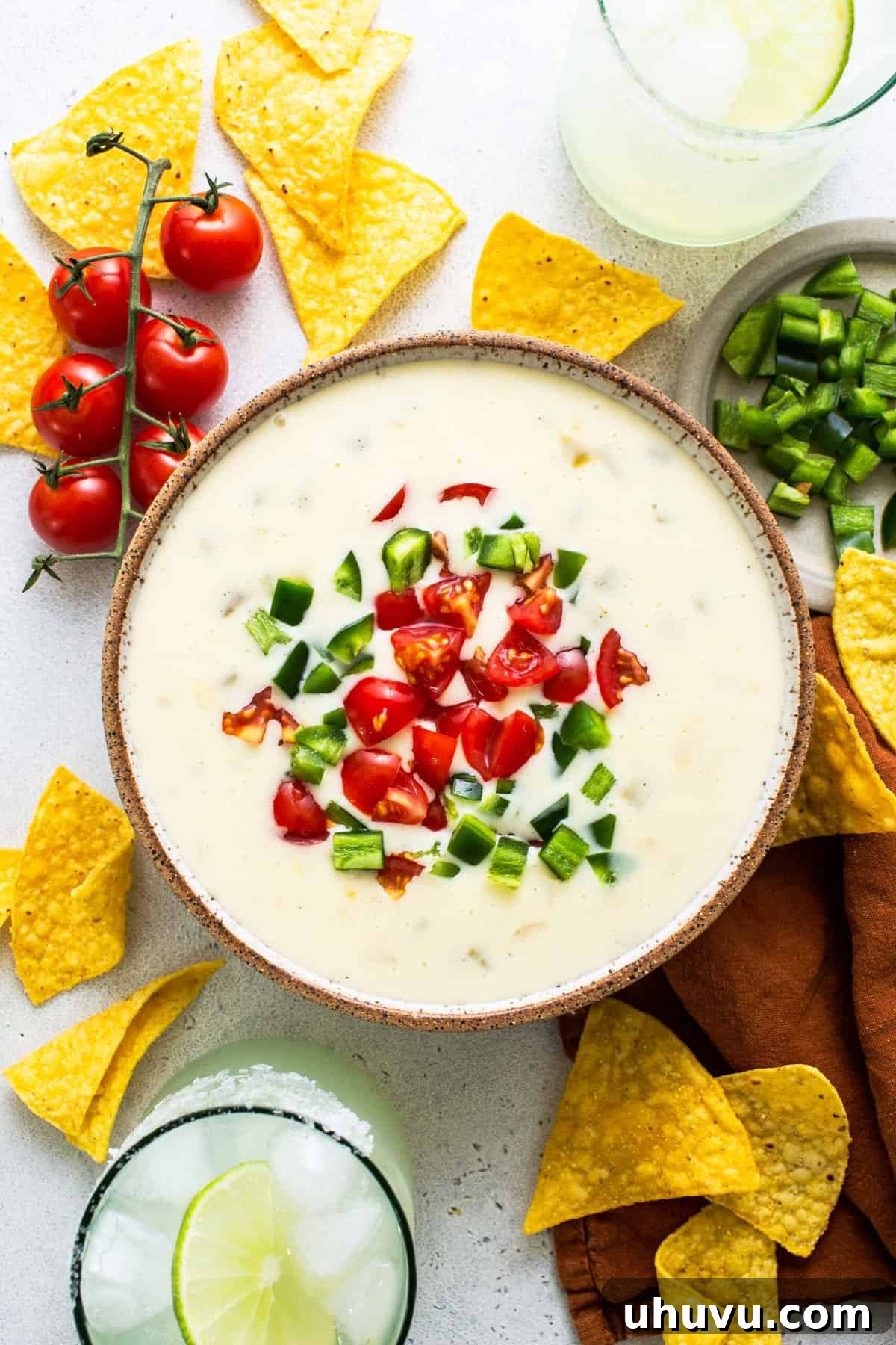 Pure White Cheese 7 A bowl of vibrant Queso Blanco, generously topped with fresh diced tomatoes and bright green jalapeño slices, ready to be enjoyed.
