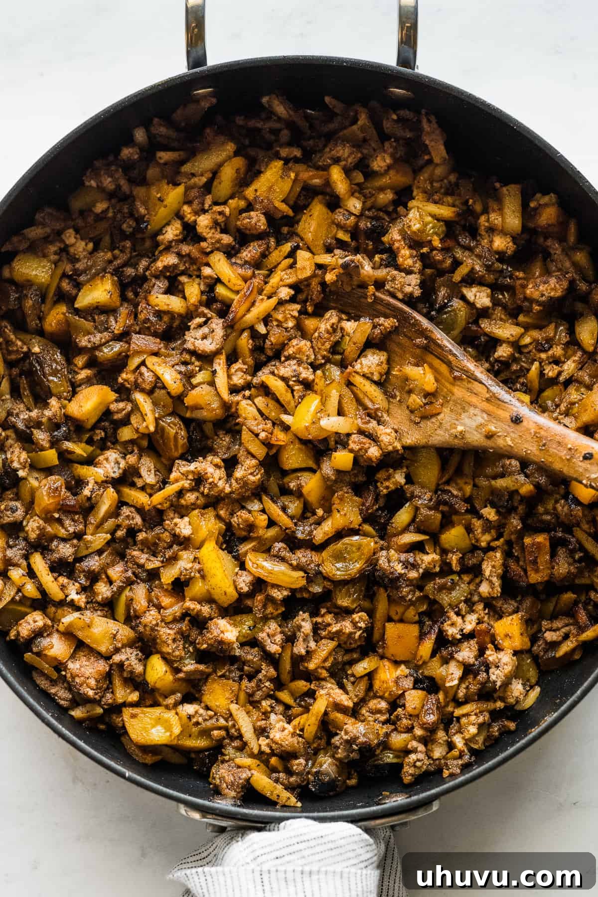 The cooked filling for chiles en nogada made from dried fruits, ground beef, and ground pork in a skillet.