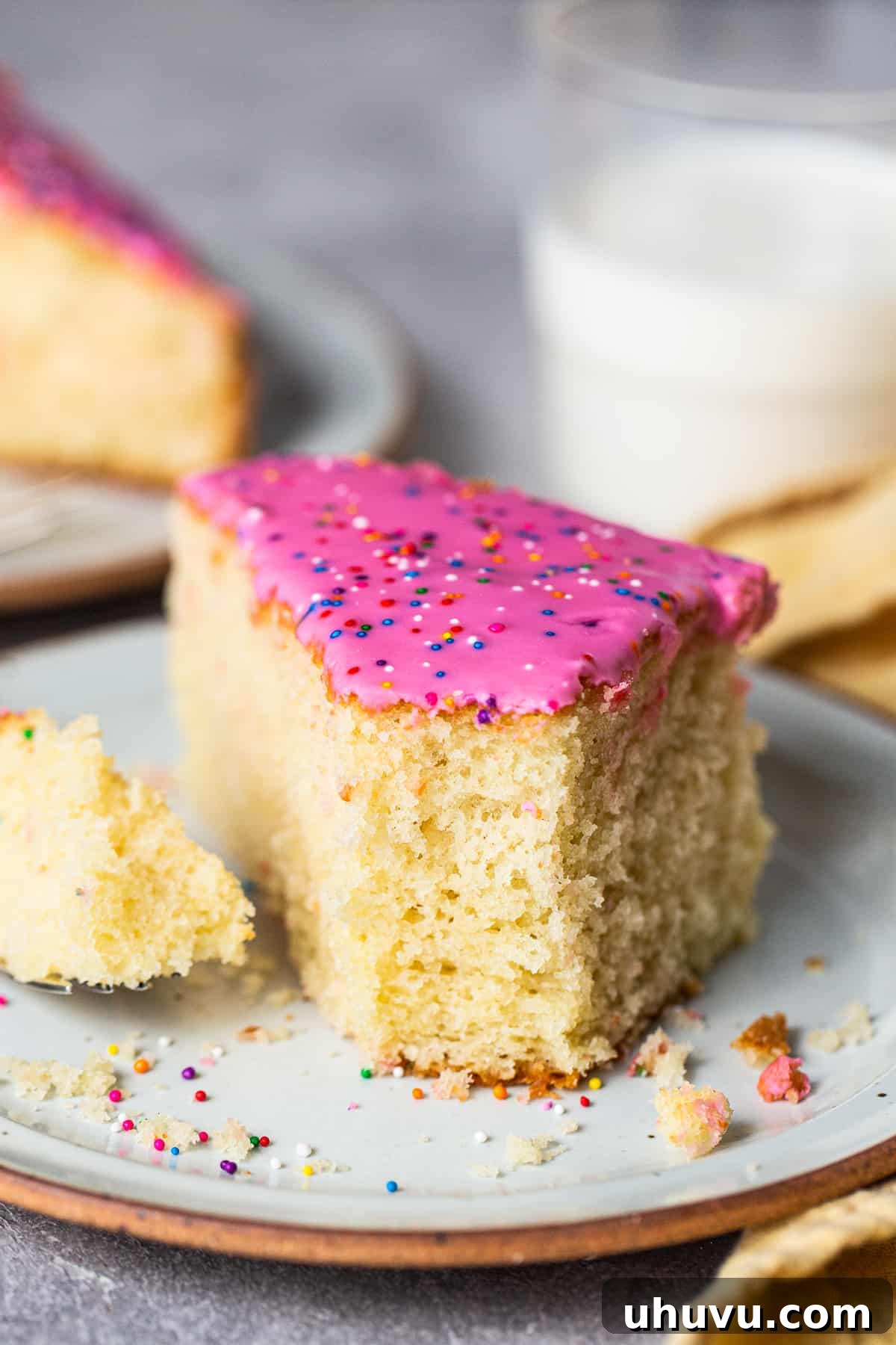 Mexico's Iconic Pink Cortadillo 8 A slice of fluffy cortadillo bread on a plate with a bite taken out, showing its tender crumb and pink icing.