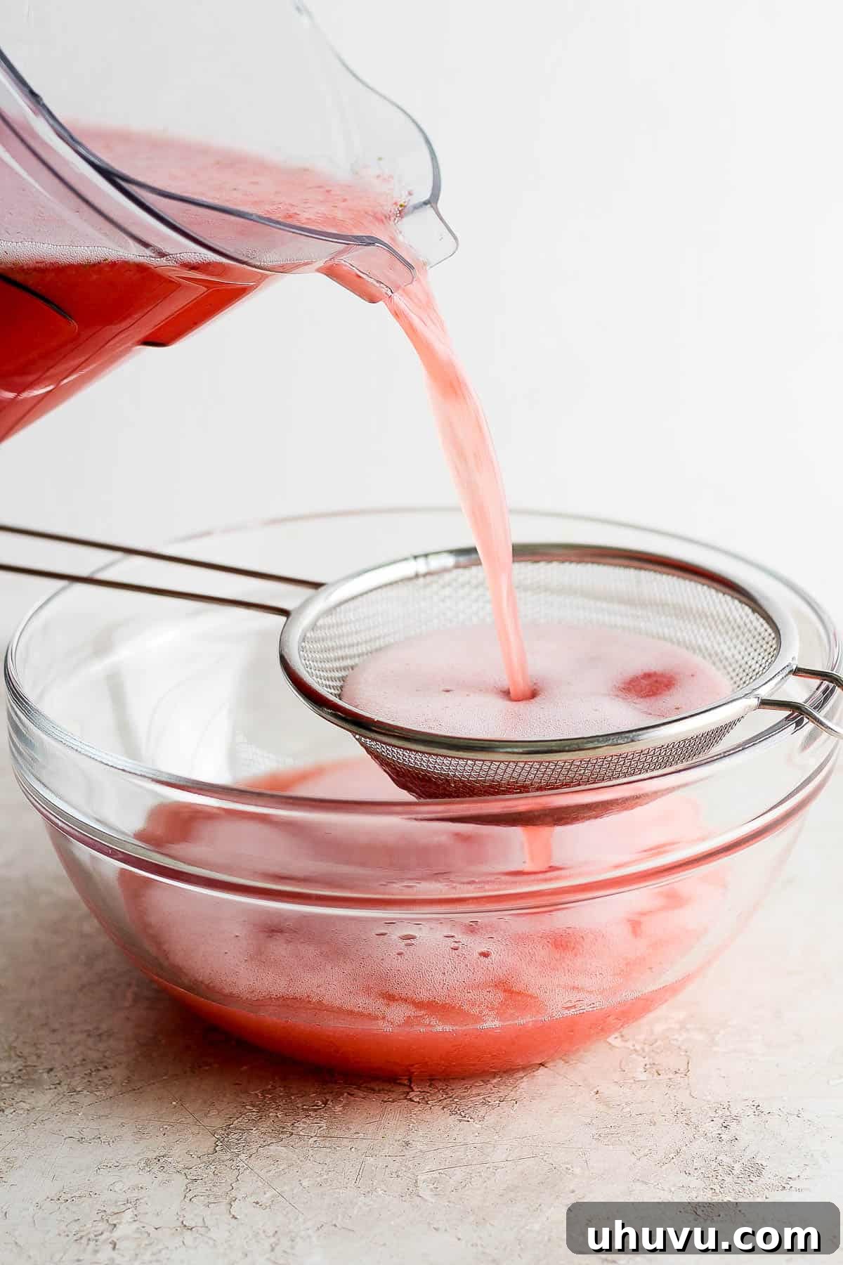 Refreshing Strawberry Sip 6 Agua de fresa (strawberry agua fresca) being poured through a strainer.