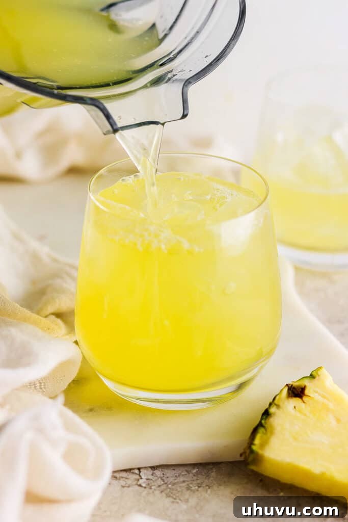 Tropical Pineapple Quencher 7 Agua de pina being poured into a glass with ice.