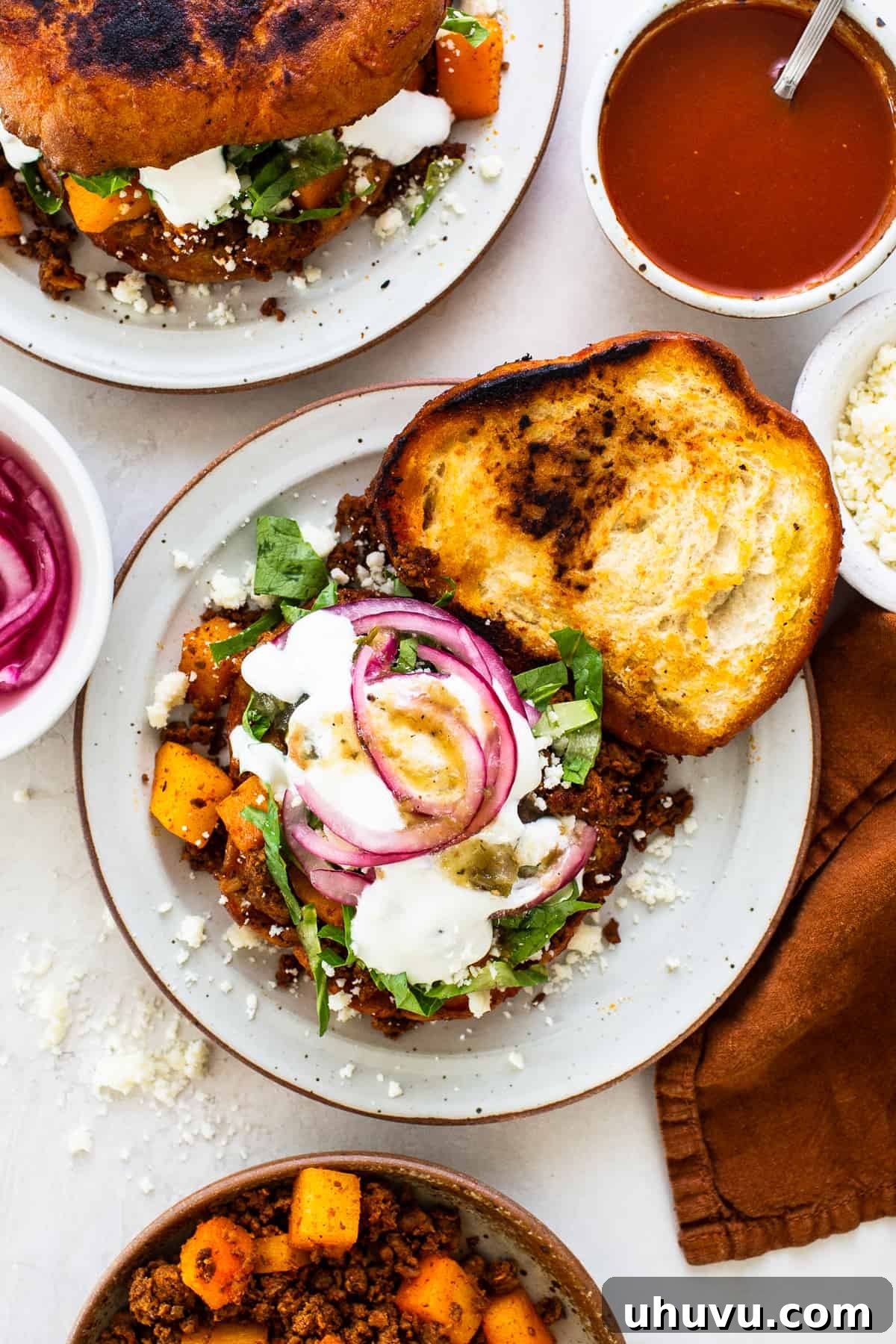 A pambazo with a chorizo and potato filling, topped with lettuce, mexican crema, red onions, and salsa verde.