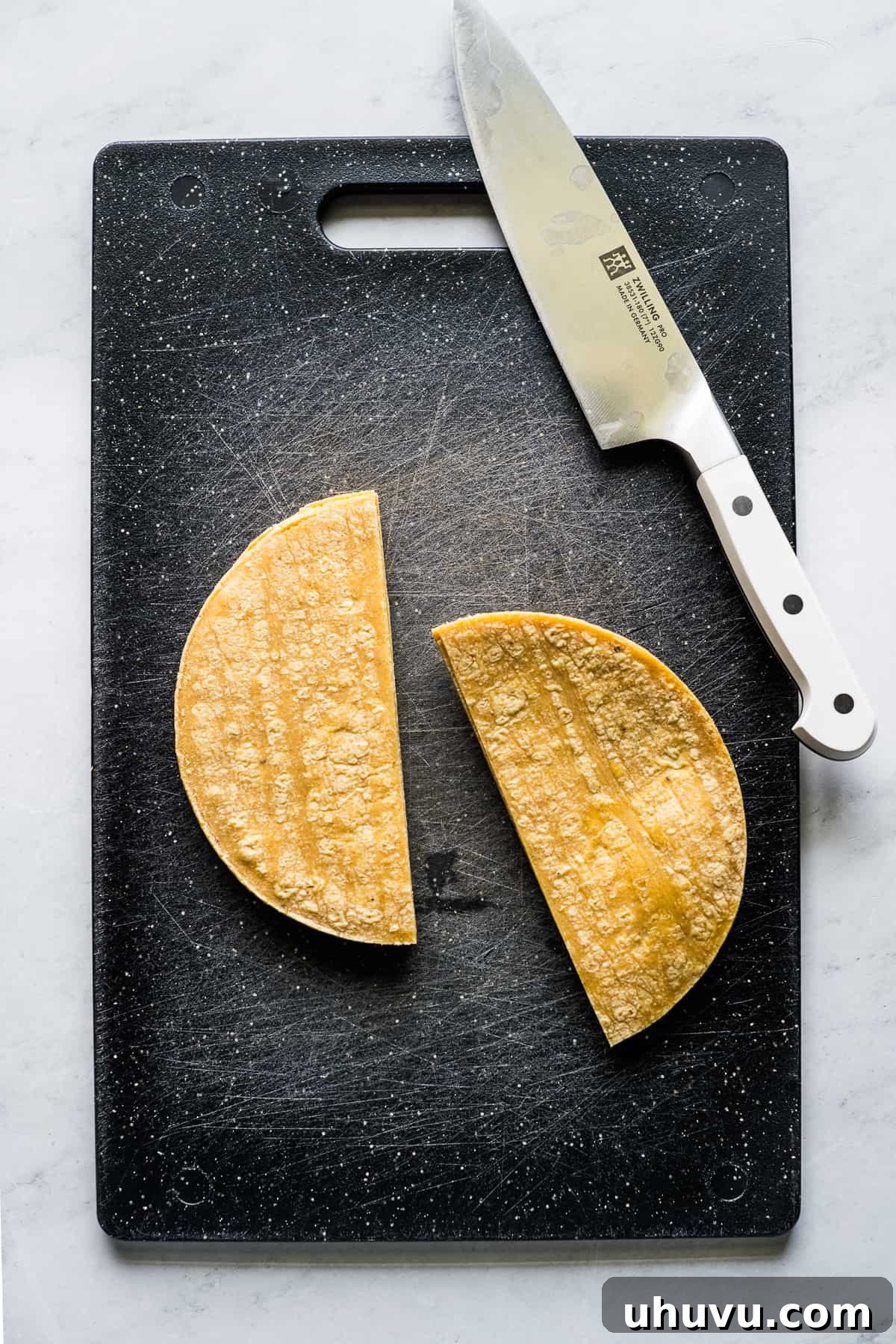 Tortilla Crisps 4 Corn tortillas neatly cut in half, preparing for the next step of slicing into strips.