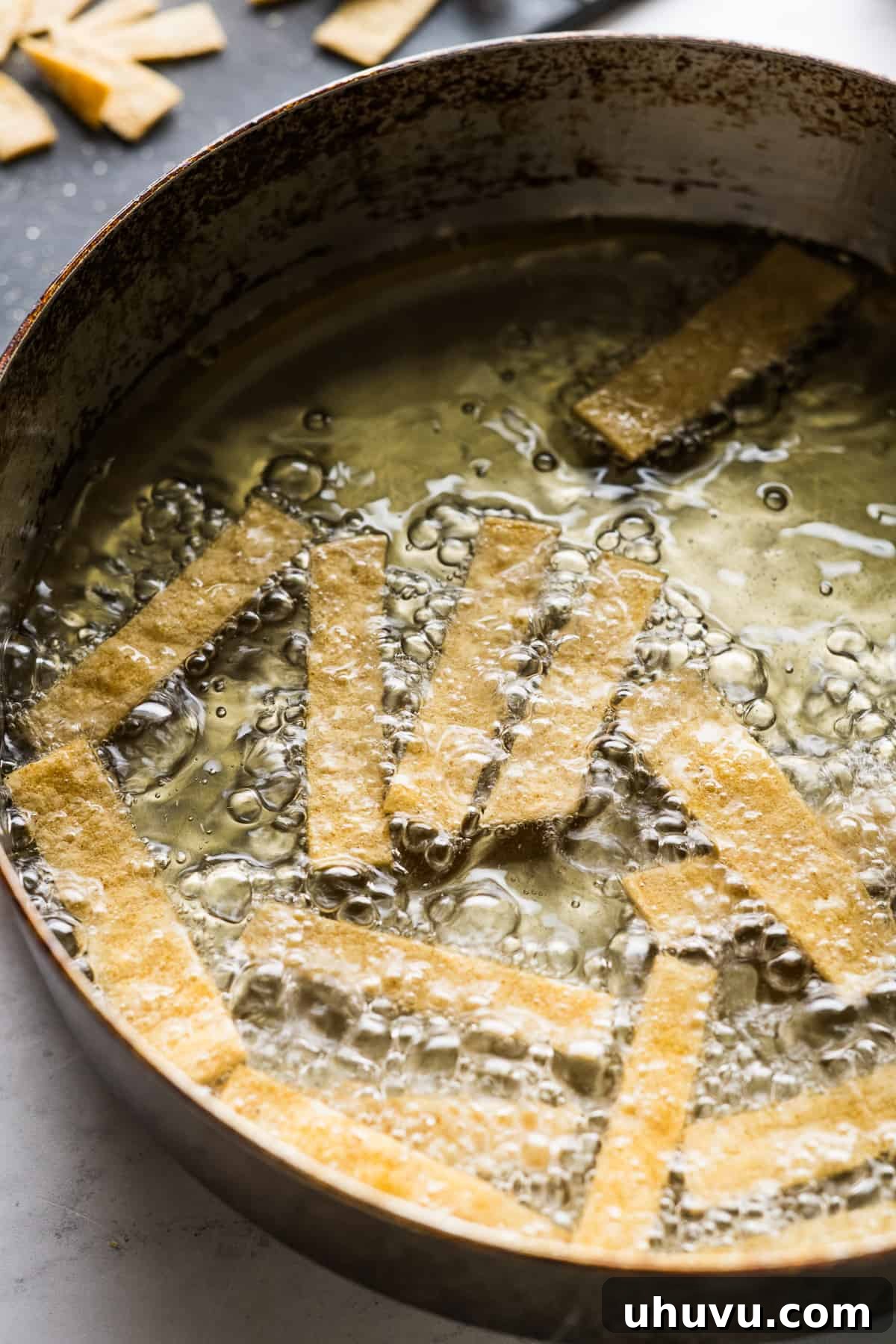 Tortilla Crisps 7 Tortilla strips sizzling and browning in a pan of hot oil, illustrating the frying process.