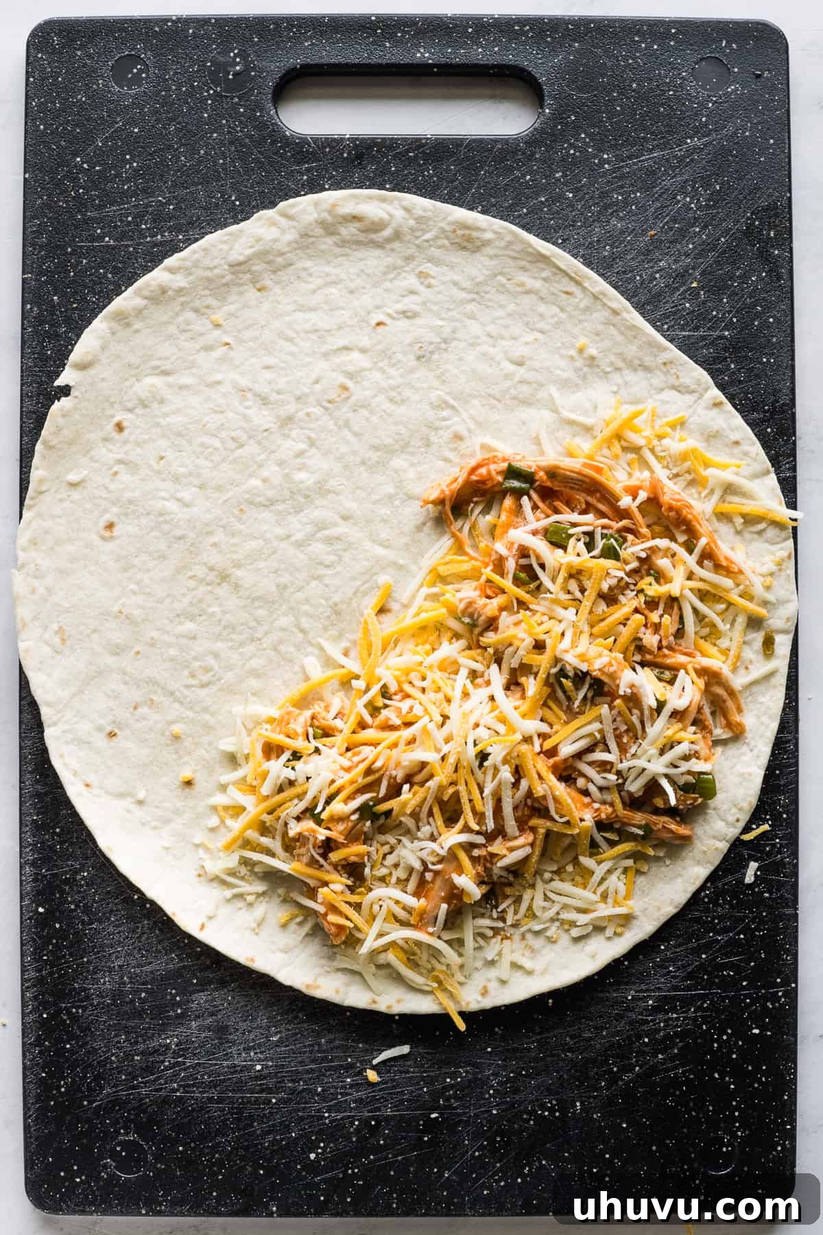 Zesty Buffalo Chicken Melts 6 A large flour tortilla filled with buffalo chicken mixture and shredded cheese, ready to be folded and cooked.