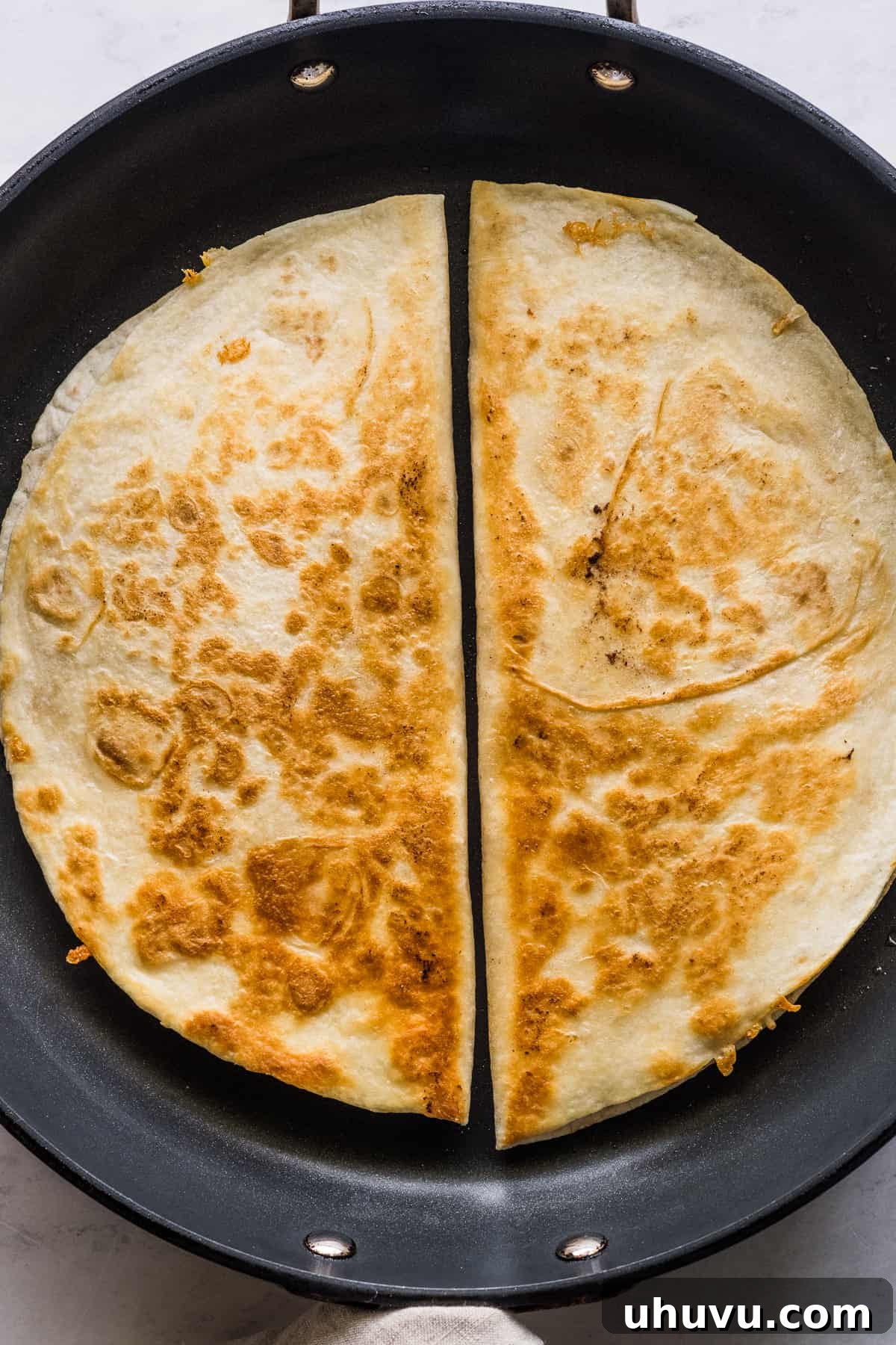 Zesty Buffalo Chicken Melts 7 Two buffalo chicken quesadillas cooking in a large nonstick skillet, turning golden brown.