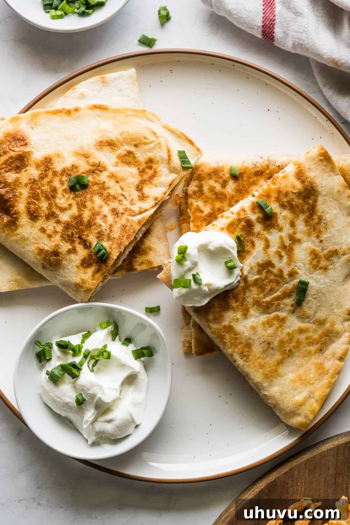 Zesty Buffalo Chicken Melts 8 A freshly cooked buffalo chicken quesadilla on a plate, served with a dollop of sour cream.