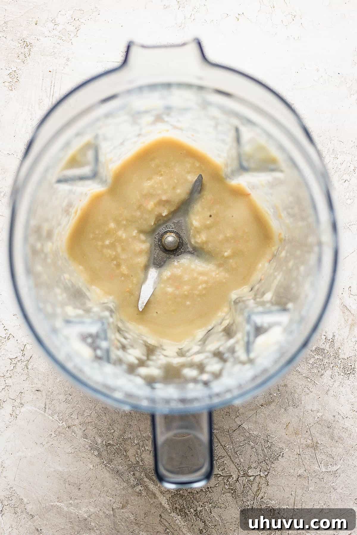 A blender containing a smooth, creamy mixture of blended cannellini beans and chicken broth, ready to be added to the chili.