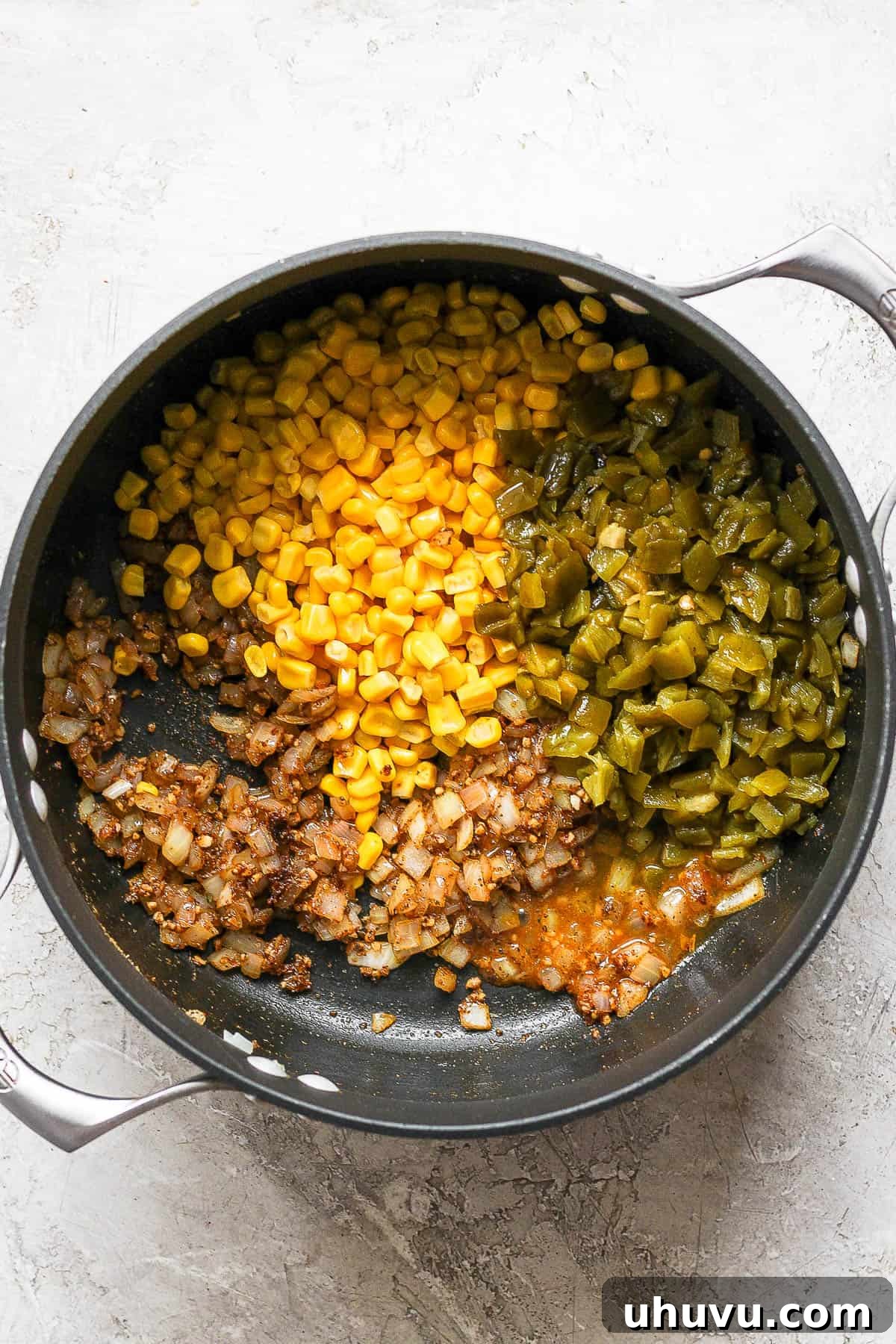 The vibrant medley of corn and diced green chiles cooking in a pot, adding color and flavor to the white chicken chili base.