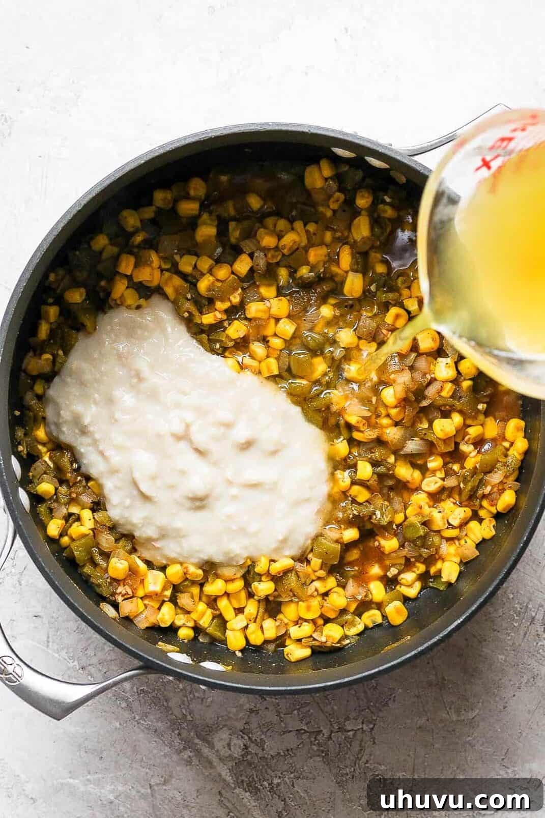 The smooth, blended cannellini bean and broth mixture being poured into a large pot, ready to combine with the sautéed vegetables and spices to create the base of the white chicken chili.