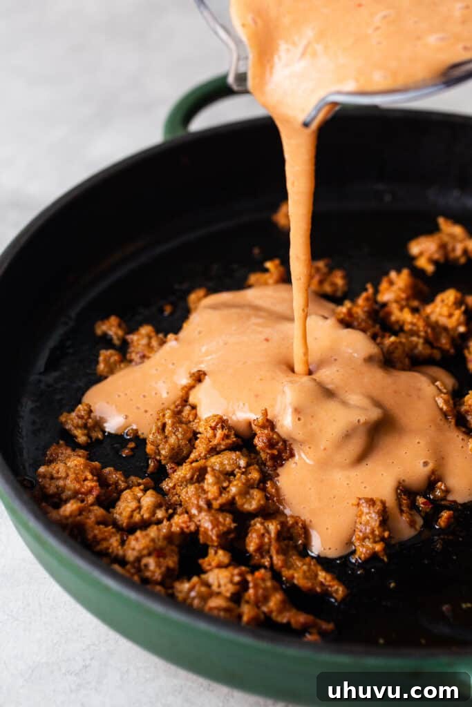 Decadent Pork Beans 5 Blended pinto beans being poured in a skillet with chorizo.