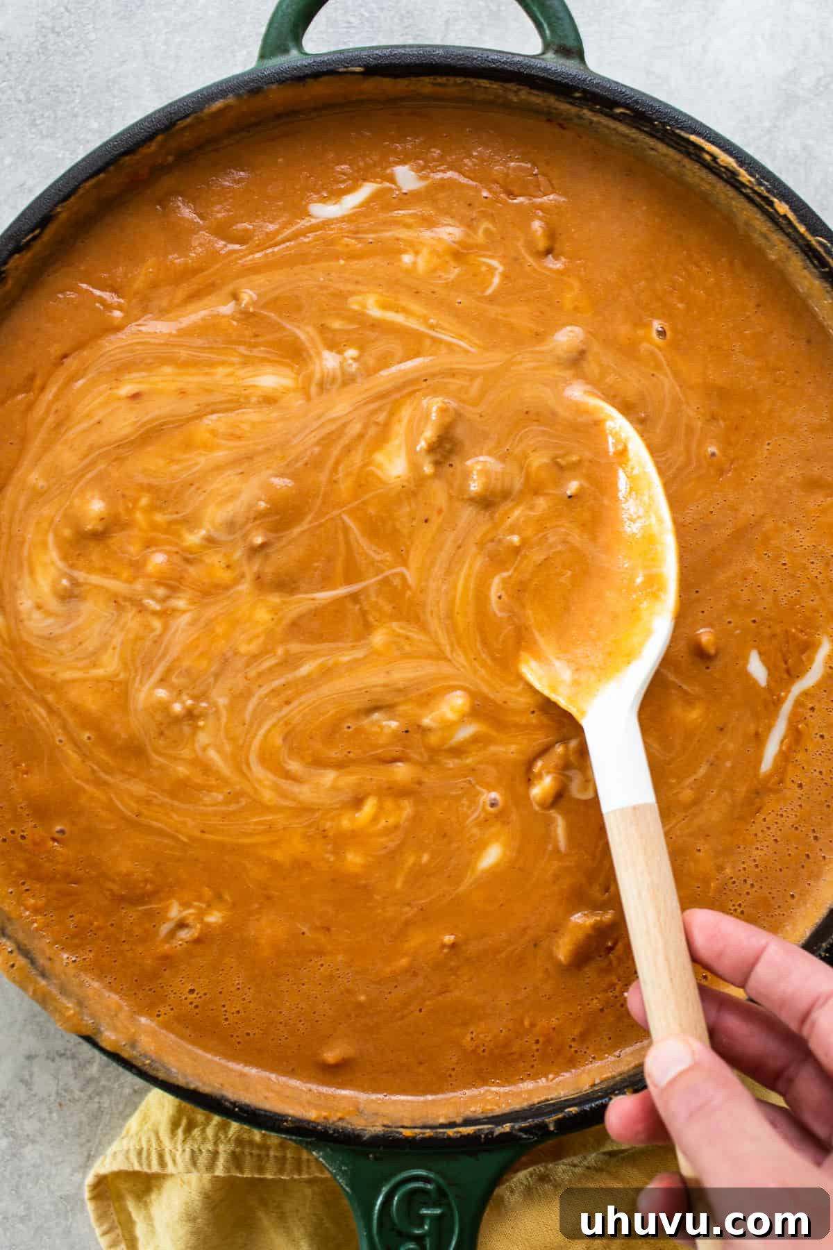Decadent Pork Beans 6 A wooden spoon stirring a skillet of frijoles puercos.