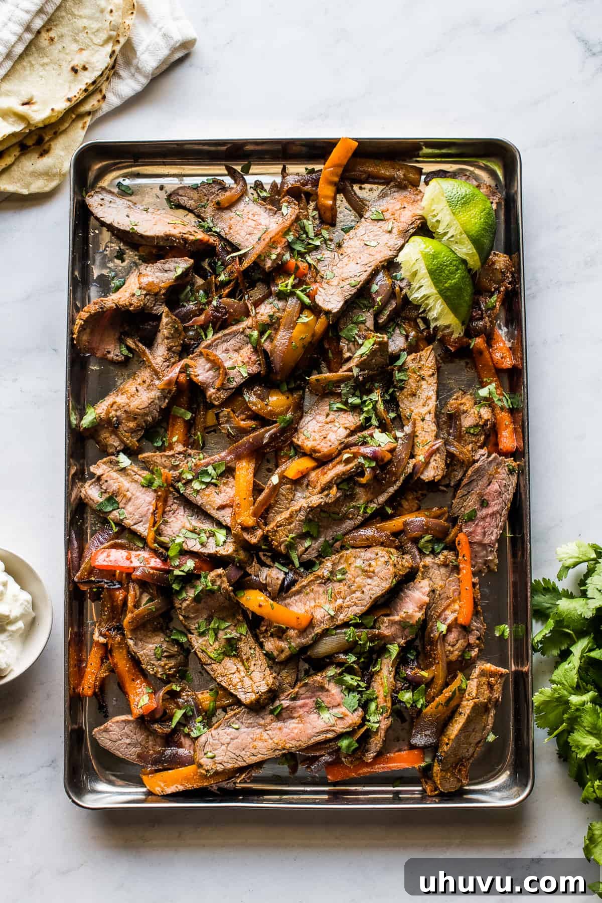 Sheet pan steak fajitas topped with chopped cilantro.