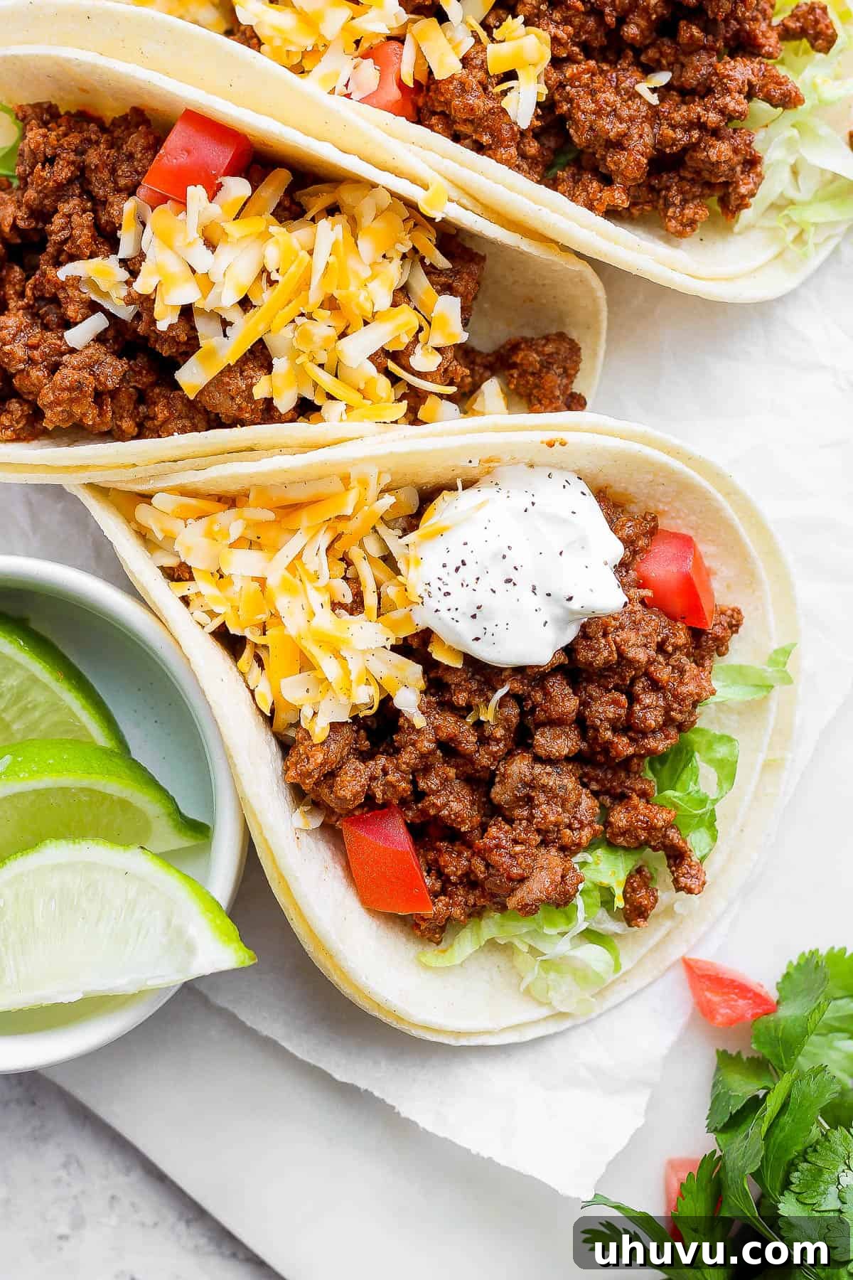 Ground beef tacos with shredded lettuce, cheese, tomatoes, and sour cream.