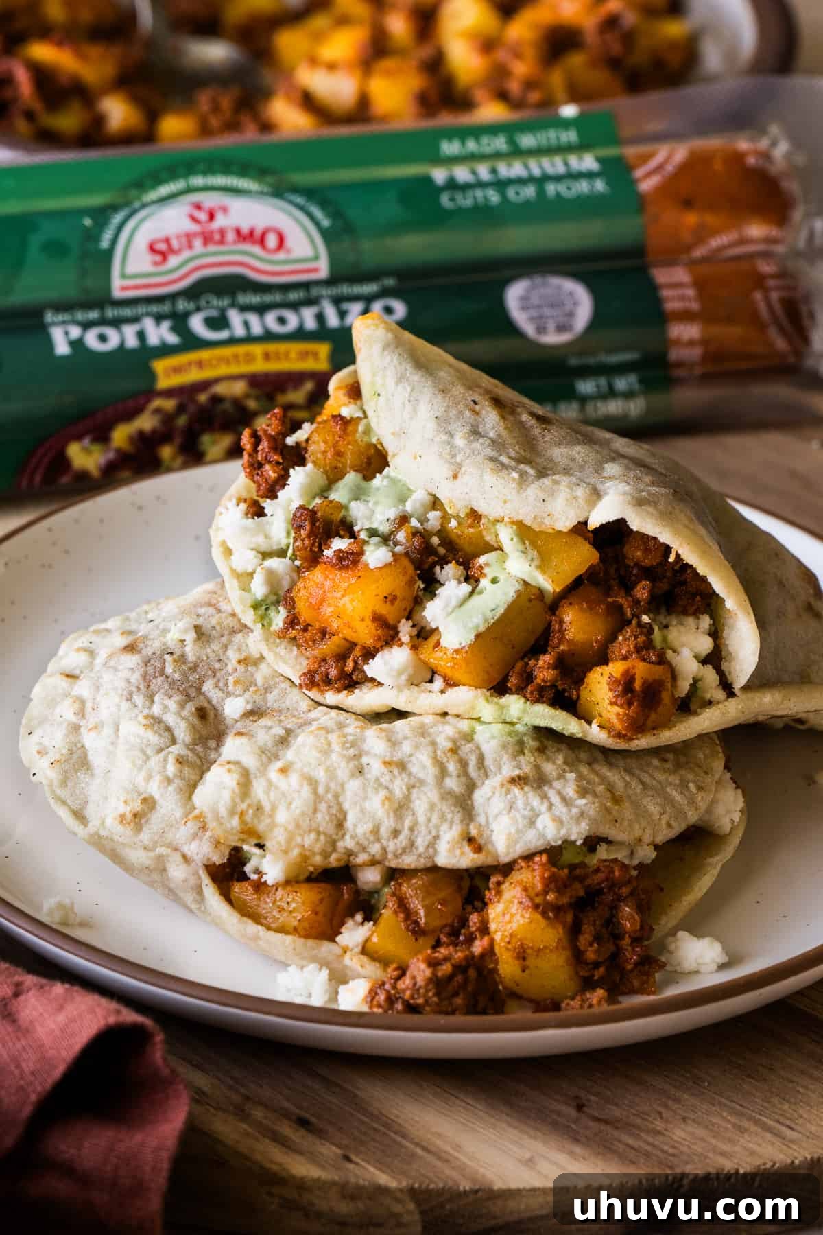 Gorditas filled with papas con chorizo on a plate, garnished with crema and queso fresco.