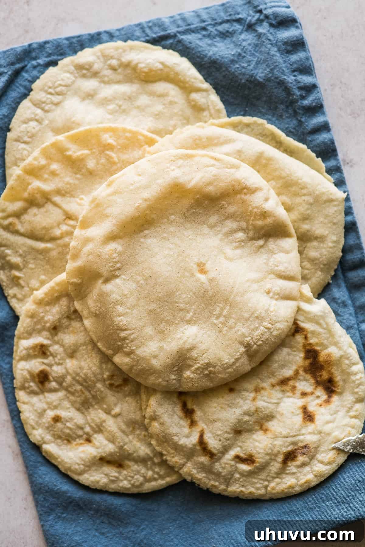 Stack of cooked gorditas on a towel, ready to be sliced and filled.