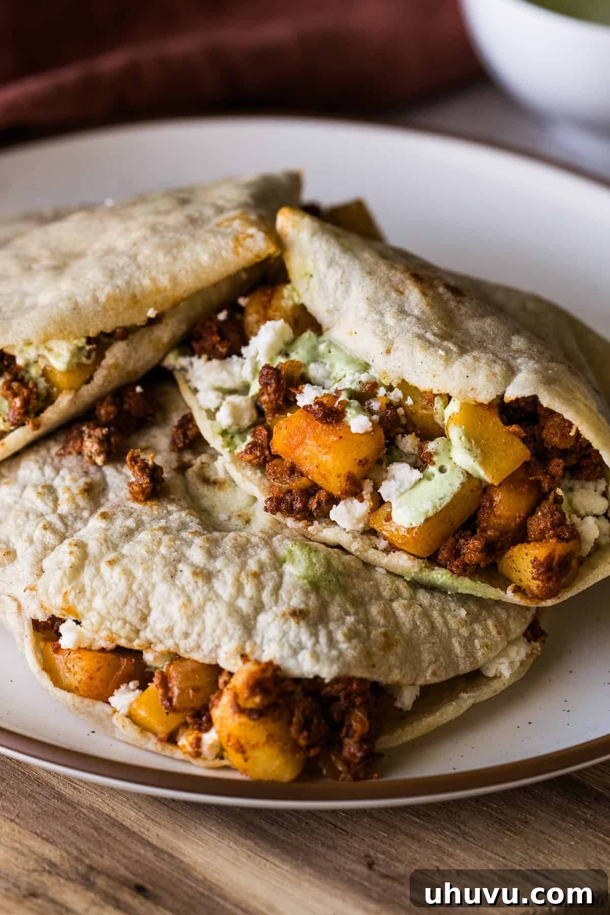 Gorditas stuffed with potatoes and chorizo, garnished and ready to eat on a plate.