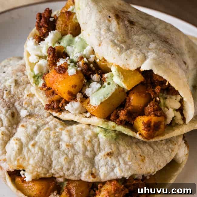 Gorditas stacked on top of one another filled with papas con chorizo and garnished with queso fresco and cilantro lime crema.