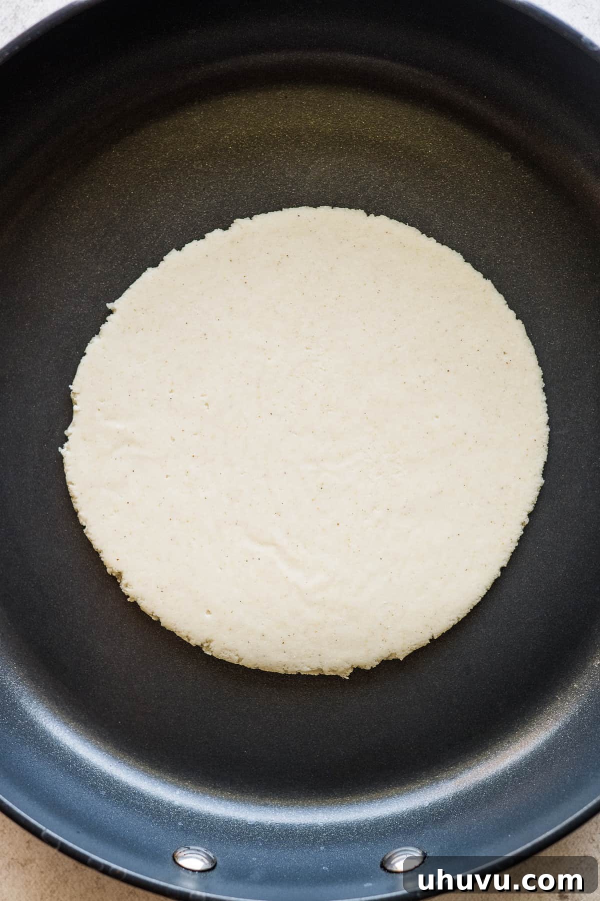 A gordita cooking and puffing up in a hot skillet.