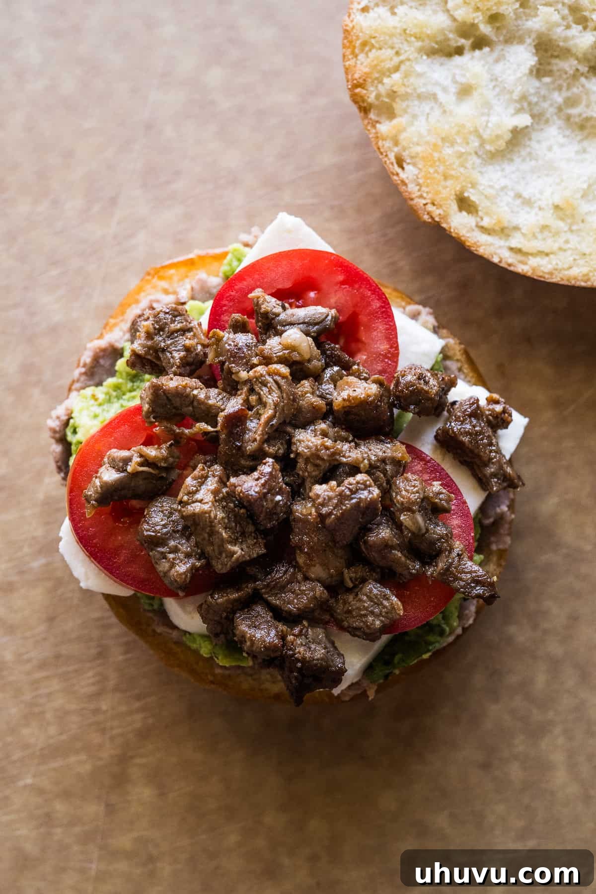Authentic Mexican Torta 13 Chuck steak, tomatoes, queso fresco, refried beans, and guacamole assembled on a telera roll.