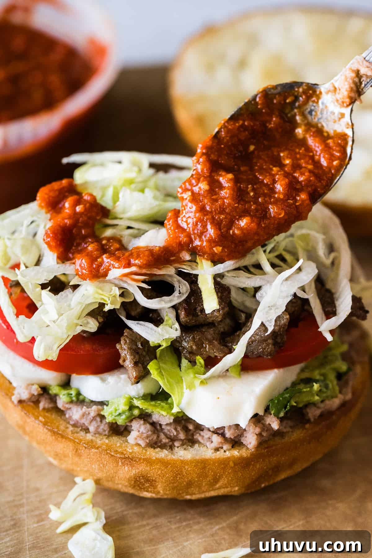 Authentic Mexican Torta 14 A vibrant red salsa being drizzled over a completed Torta.