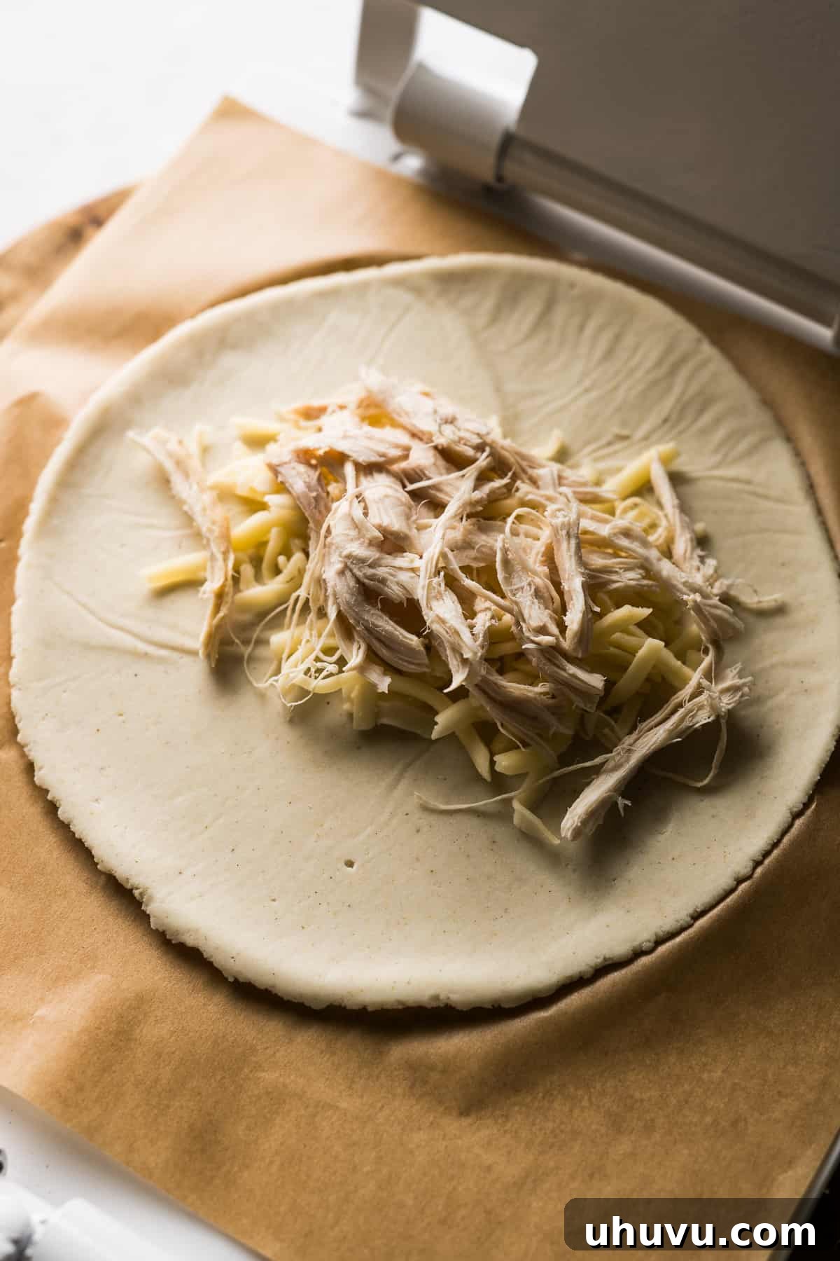 Golden Fried Cheesy Pockets 8 A circular masa disc with a generous portion of shredded chicken and cheese placed in its center, ready for folding.