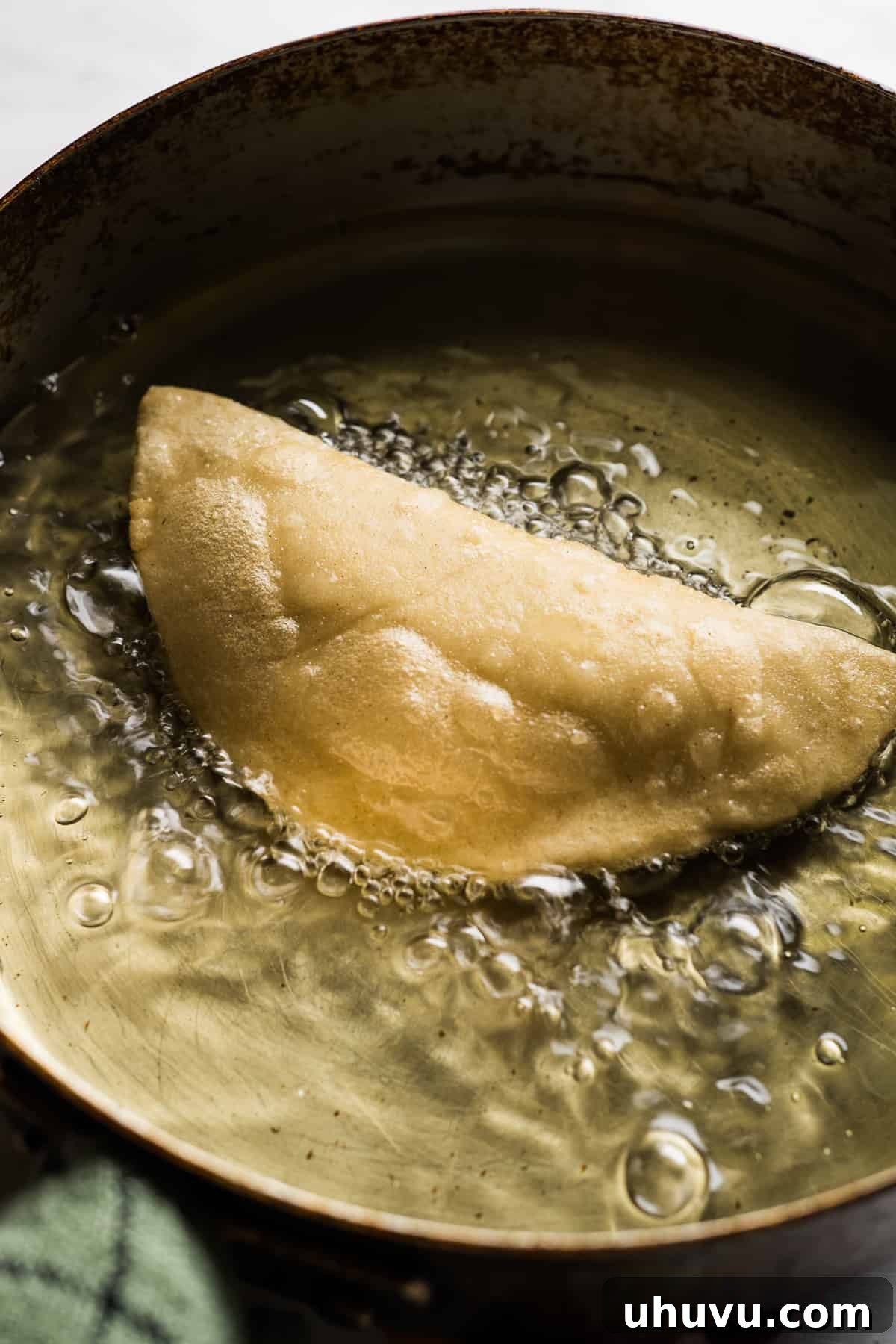 Golden Fried Cheesy Pockets 10 A traditional masa quesadilla being carefully fried in hot oil within a deep skillet, achieving a golden crisp.