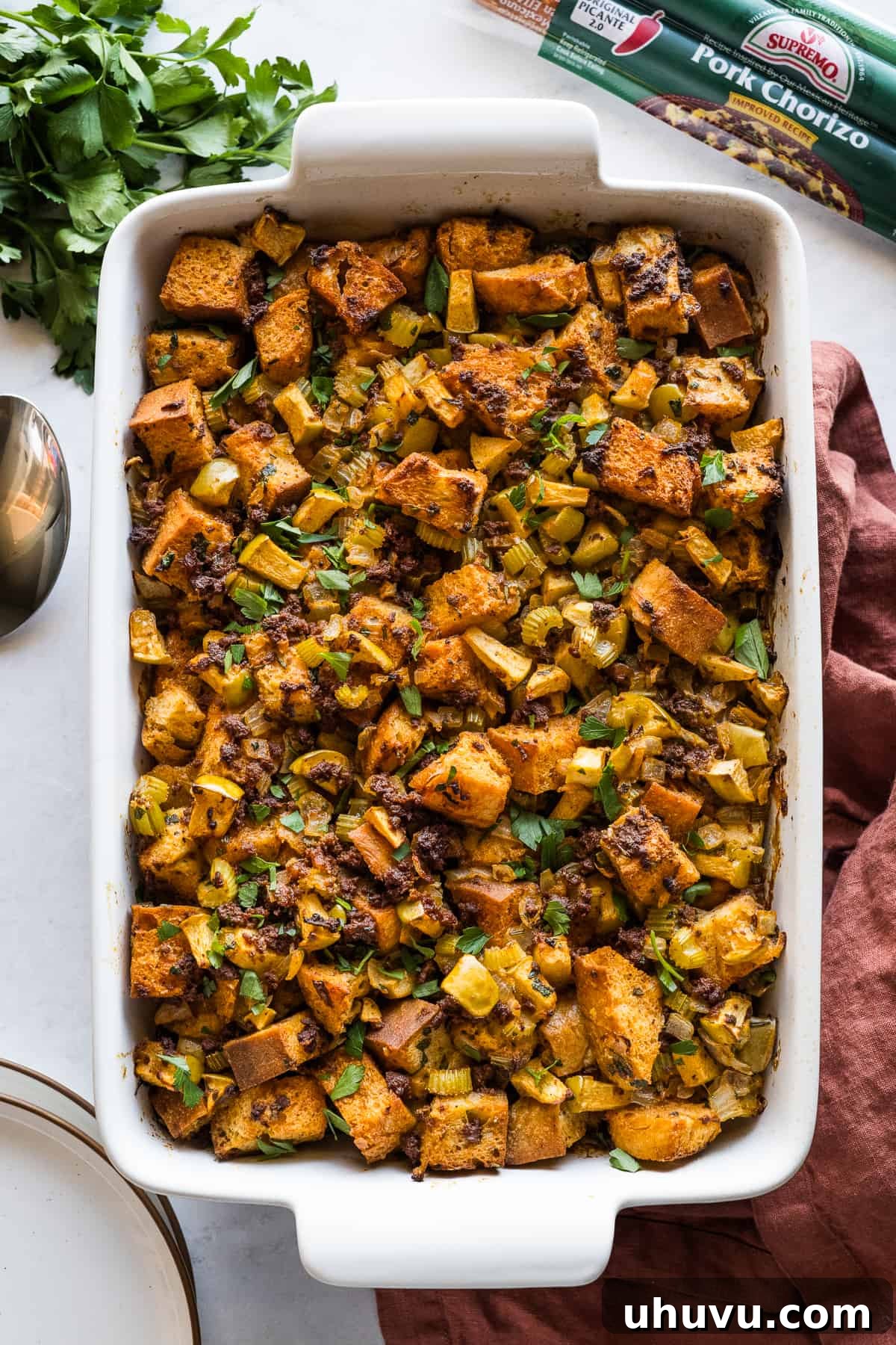Spicy Chorizo Stuffing 2 A golden-brown baking dish containing Chorizo Stuffing, generously garnished with vibrant fresh parsley, ready to be served at a Thanksgiving feast.