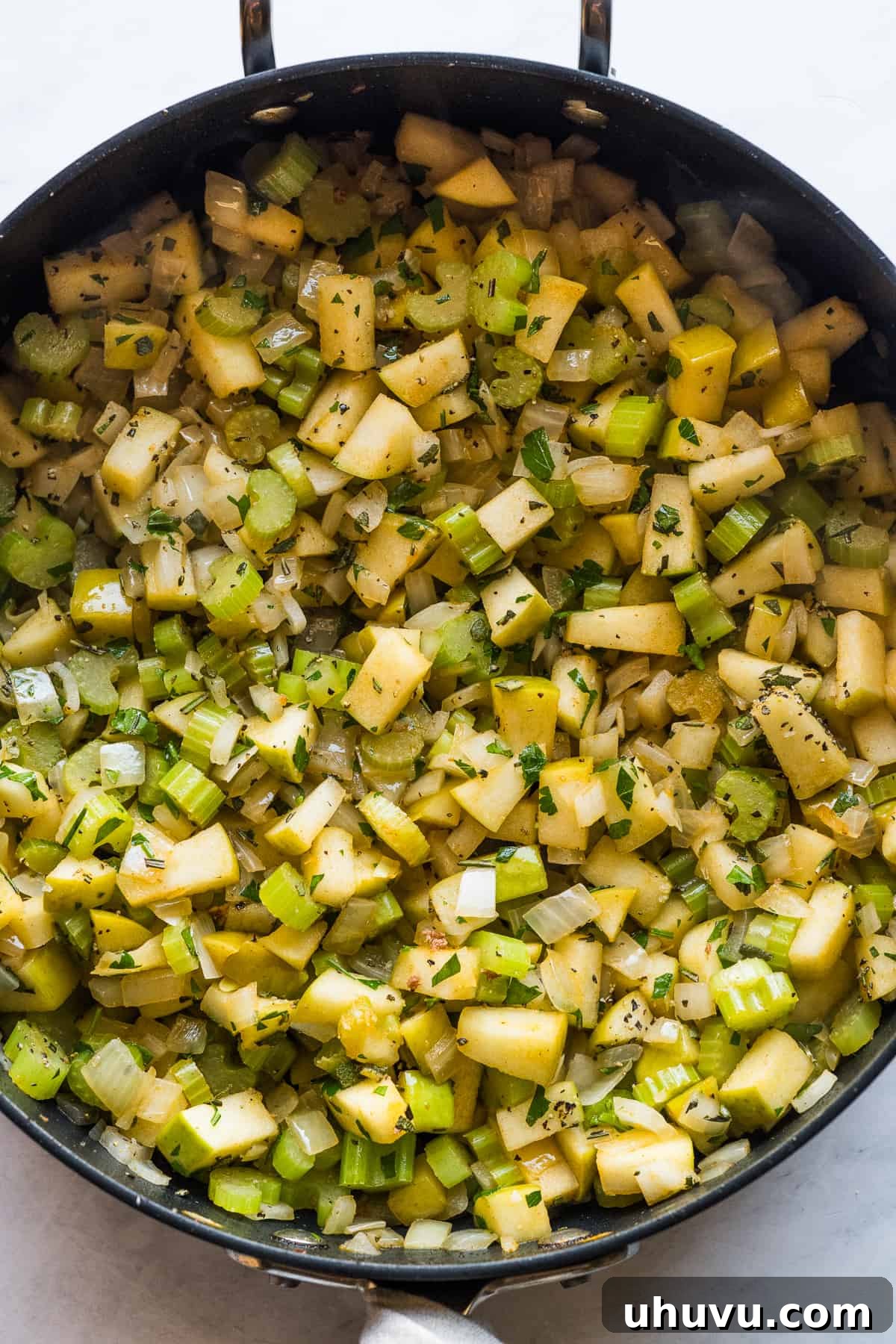 Spicy Chorizo Stuffing 6 A skillet containing a colorful mixture of sautéed celery, onions, and Granny Smith apples, cooked until tender and fragrant.