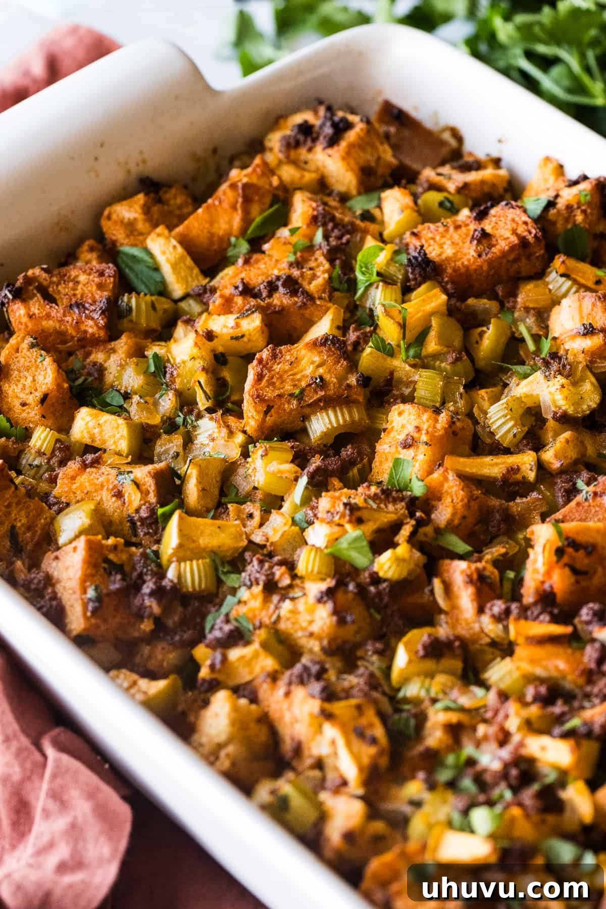 Spicy Chorizo Stuffing 10 A close-up shot of a baking dish overflowing with beautifully baked Chorizo Stuffing, generously garnished with fresh parsley, ready for a holiday meal.
