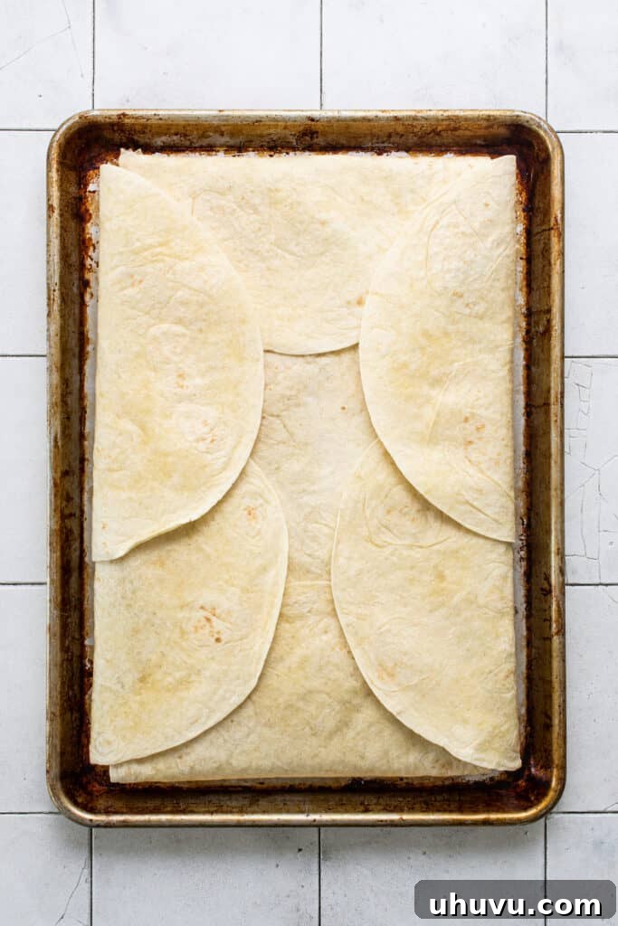 The fully assembled sheet pan quesadilla, with all tortillas folded over the rich filling, brushed with butter, and poised for baking to golden perfection.