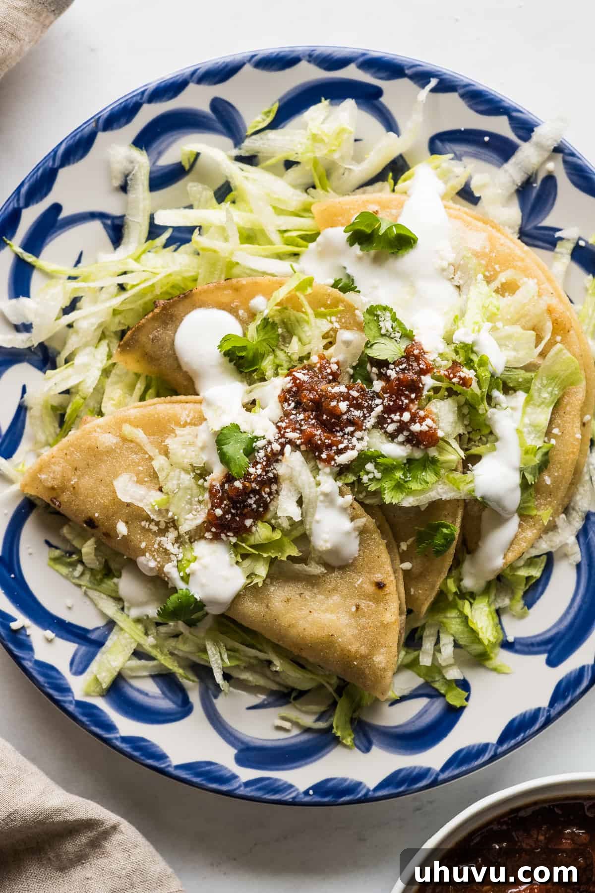 Golden Crispy Tacos 2 Tacos dorados on a plate served with shredded lettuce, Mexican crema, and a roasted tomato salsa.