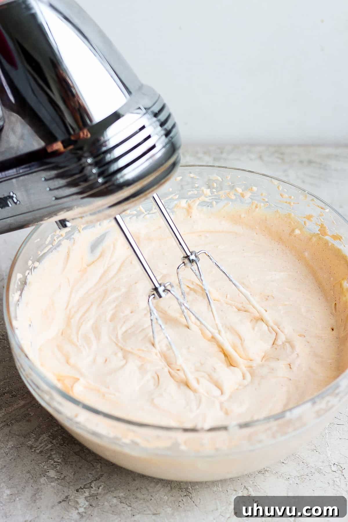 Ultimate Taco Party Dip 5 The creamy base layer of taco dip being mixed with an electric mixer, achieving a smooth and well-combined consistency.