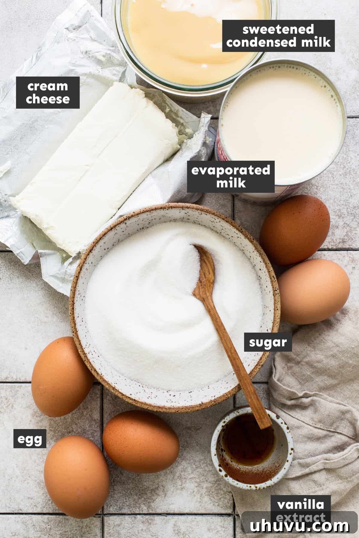 Rich Cheese Flan 3 Various ingredients for making Flan de Queso laid out neatly on a wooden table, including eggs, milk, cream cheese, sugar, and vanilla extract.