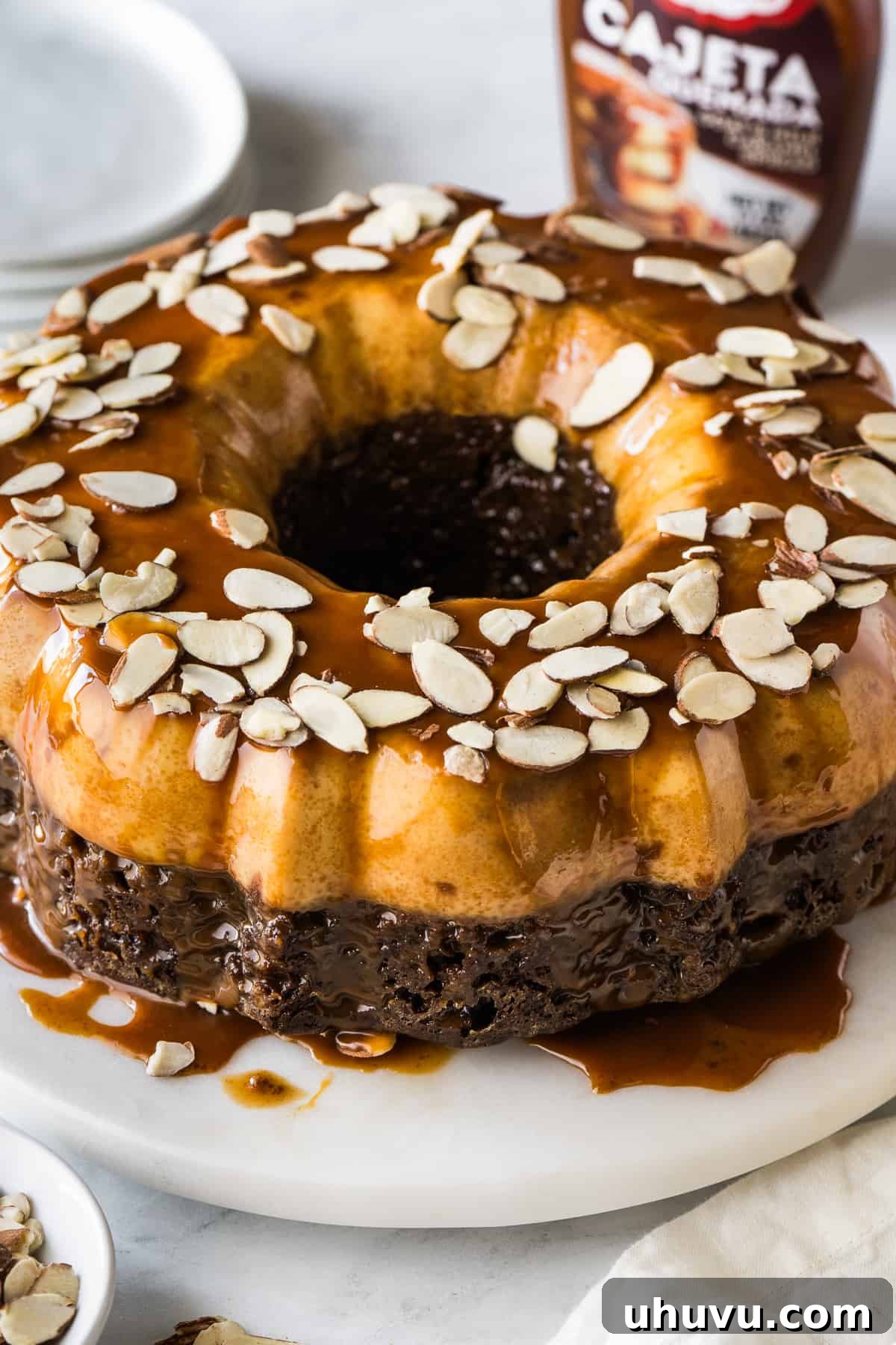 Chocolate Flan Fusion 12 The finished chocoflan, beautifully inverted and topped with a generous drizzle of rich cajeta caramel sauce and thinly sliced almonds, ready to be served.