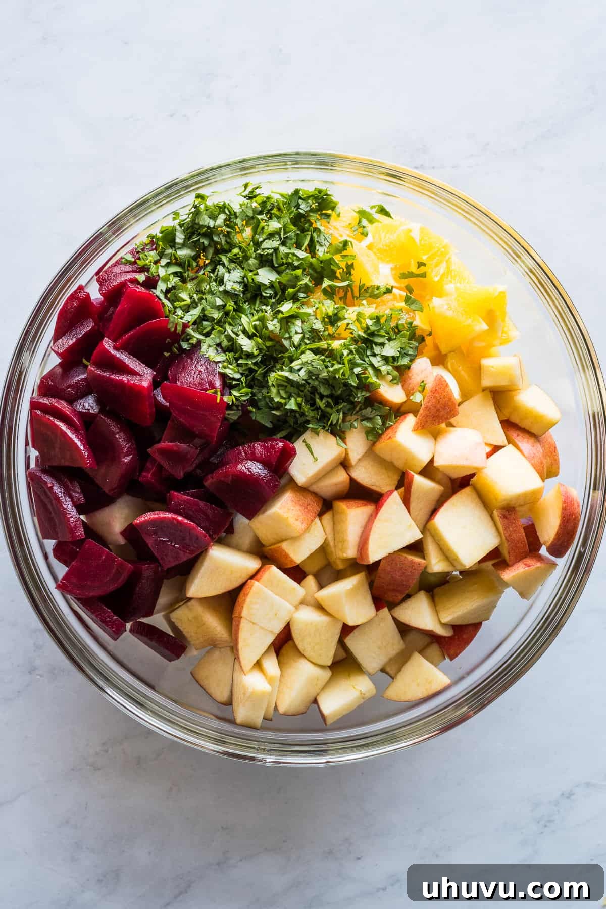 Yuletide Celebration Salad 4 A large mixing bowl filled with vibrant Ensalada de Nochebuena ingredients, including beets, apples, oranges, jicama, cilantro, and pecans, before the dressing is added.