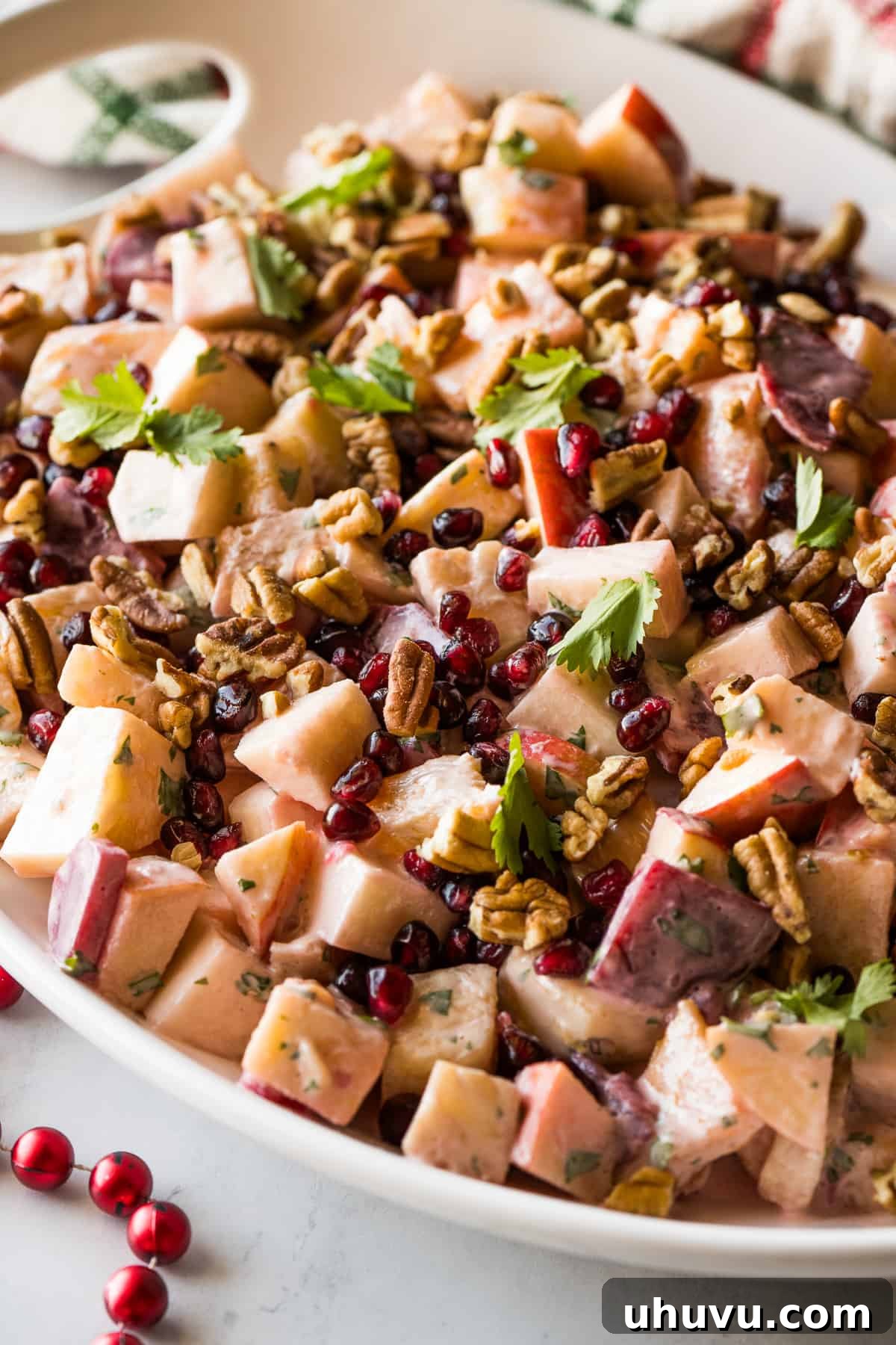 Yuletide Celebration Salad 6 A finished serving of Ensalada de Nochebuena, garnished with fresh cilantro and chopped pecans, showcasing its rich colors and inviting texture.