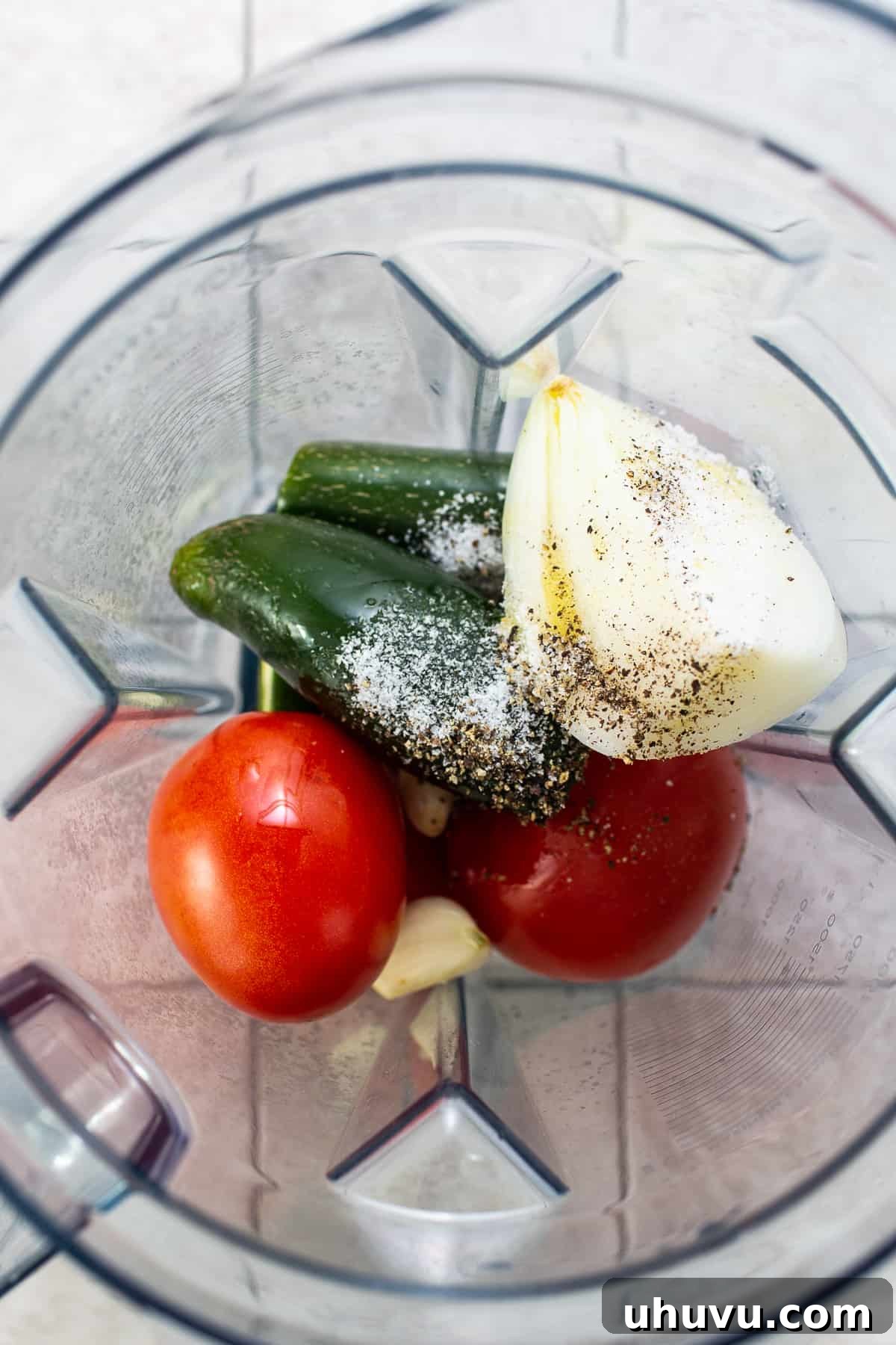 Vibrant Mexican Salsa 4 Fresh jalapeños, Roma tomatoes, onion, garlic, salt, and black pepper are shown in a blender, ready to be processed for Salsa Mexicana.