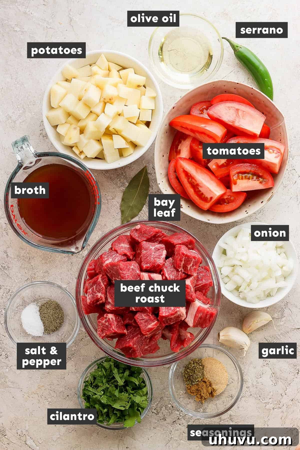 Homestyle Beef and Potatoes 3 A collection of fresh ingredients for Carne con Papas, including beef, potatoes, tomatoes, onions, garlic, and serrano peppers, neatly arranged on a rustic wooden table.