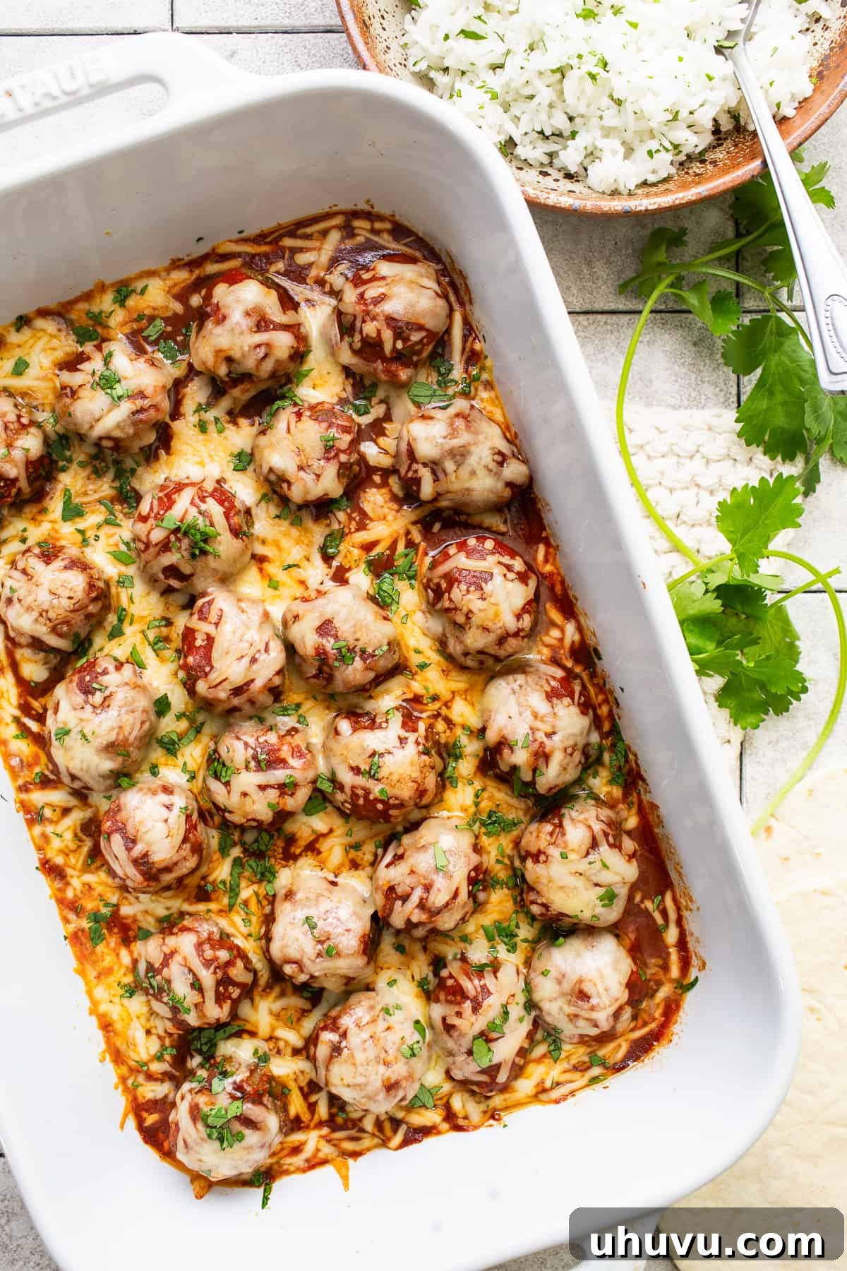 Smothered Enchilada Meatballs 2 Enchilada meatballs in a baking dish garnished with cilantro.