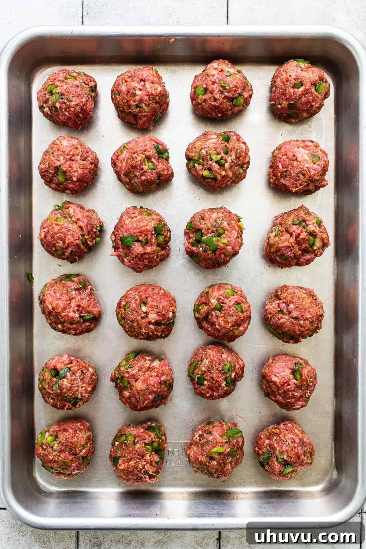 Smothered Enchilada Meatballs 4 Beef meatballs on a baking sheet.