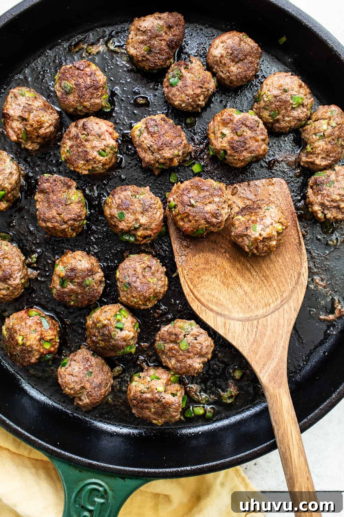 Smothered Enchilada Meatballs 5 Meatballs seared in a cast iron skillet.