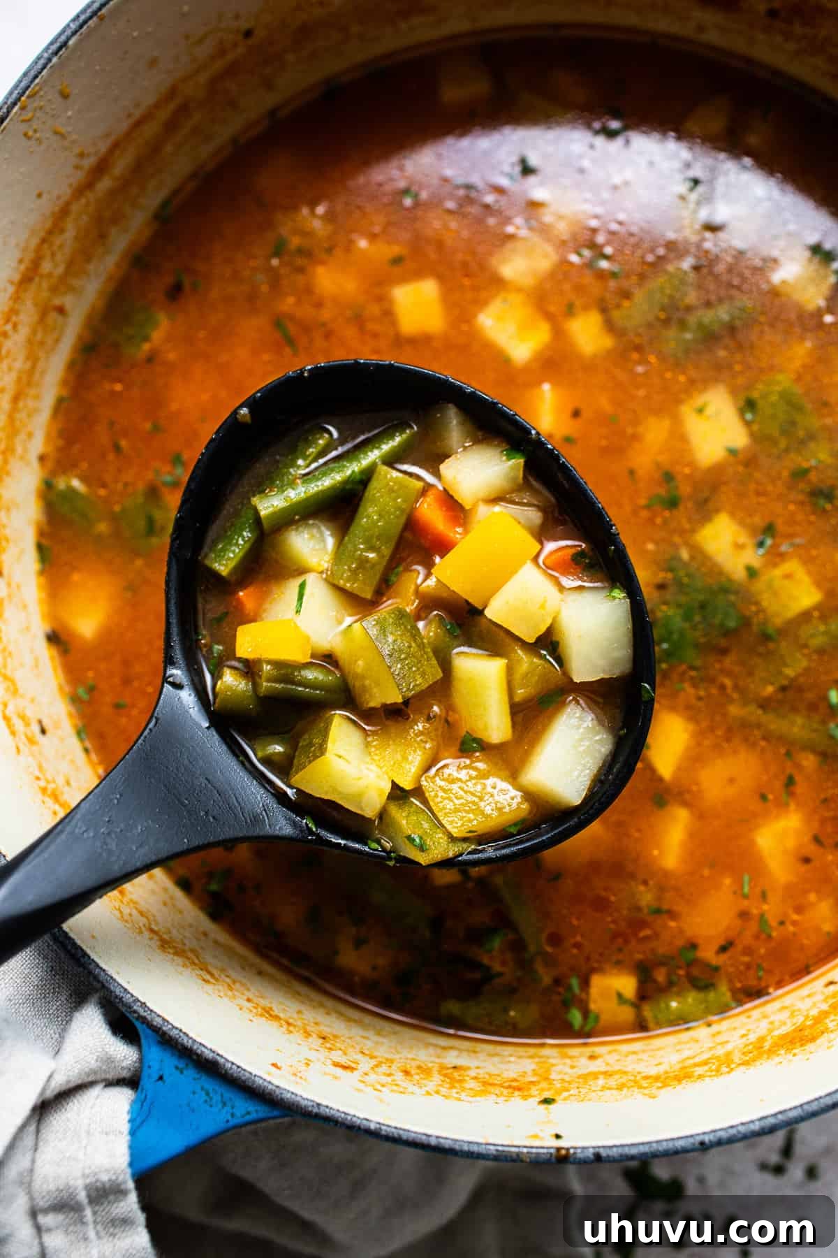 A close-up view of Mexican Vegetable Soup being served from a pot, with a ladle scooping up a portion, highlighting the vibrant vegetables and broth.