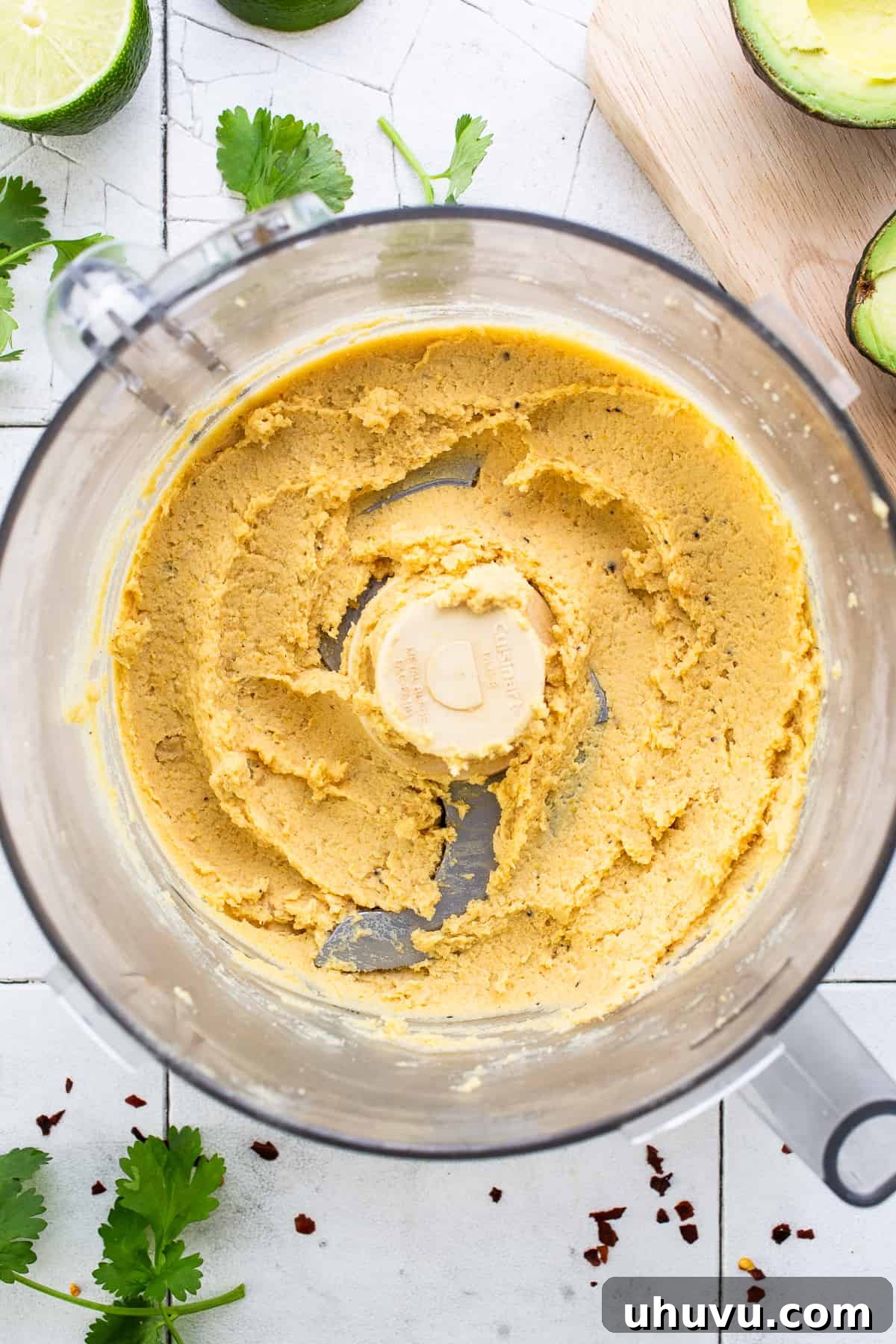 Green Goddess Hummus 4 A food processor bowl containing a smooth, creamy blend of chickpeas, tahini, olive oil, and spices, forming the base of the hummus.