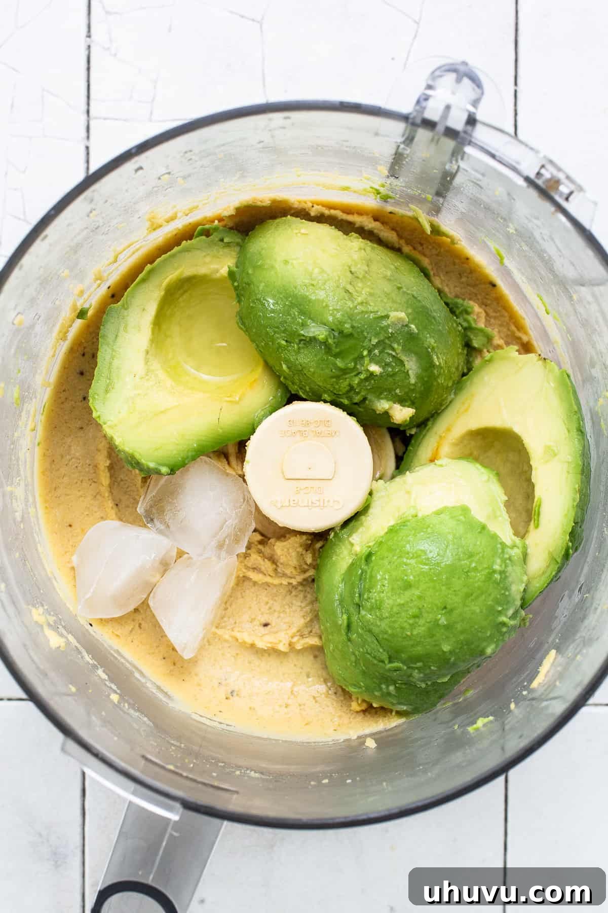 Green Goddess Hummus 5 Ripe avocados, fresh lime juice, and ice cubes added to the blended chickpea mixture in a food processor, ready for the final blend.