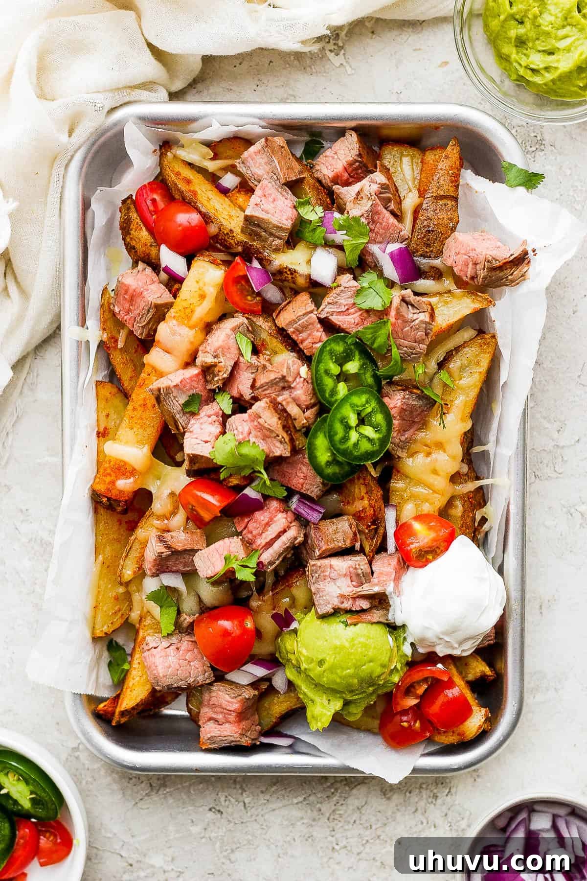 Top 20 Irresistible Mexican Bites for Your Epic Fiesta 14 A generous plate of Carne Asada Fries, loaded with toppings and served with a side of sour cream and guacamole.