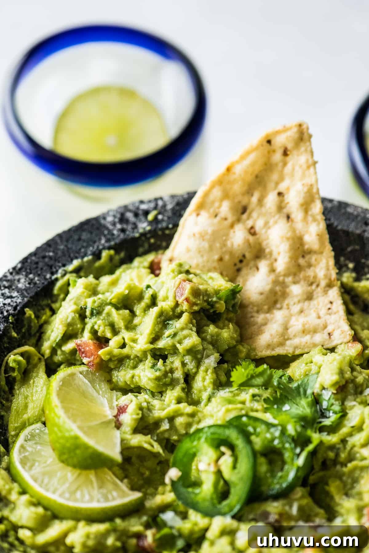 Top 20 Irresistible Mexican Bites for Your Epic Fiesta 19 Freshly made guacamole in a traditional molcajete, with a tortilla chip poised for dipping.