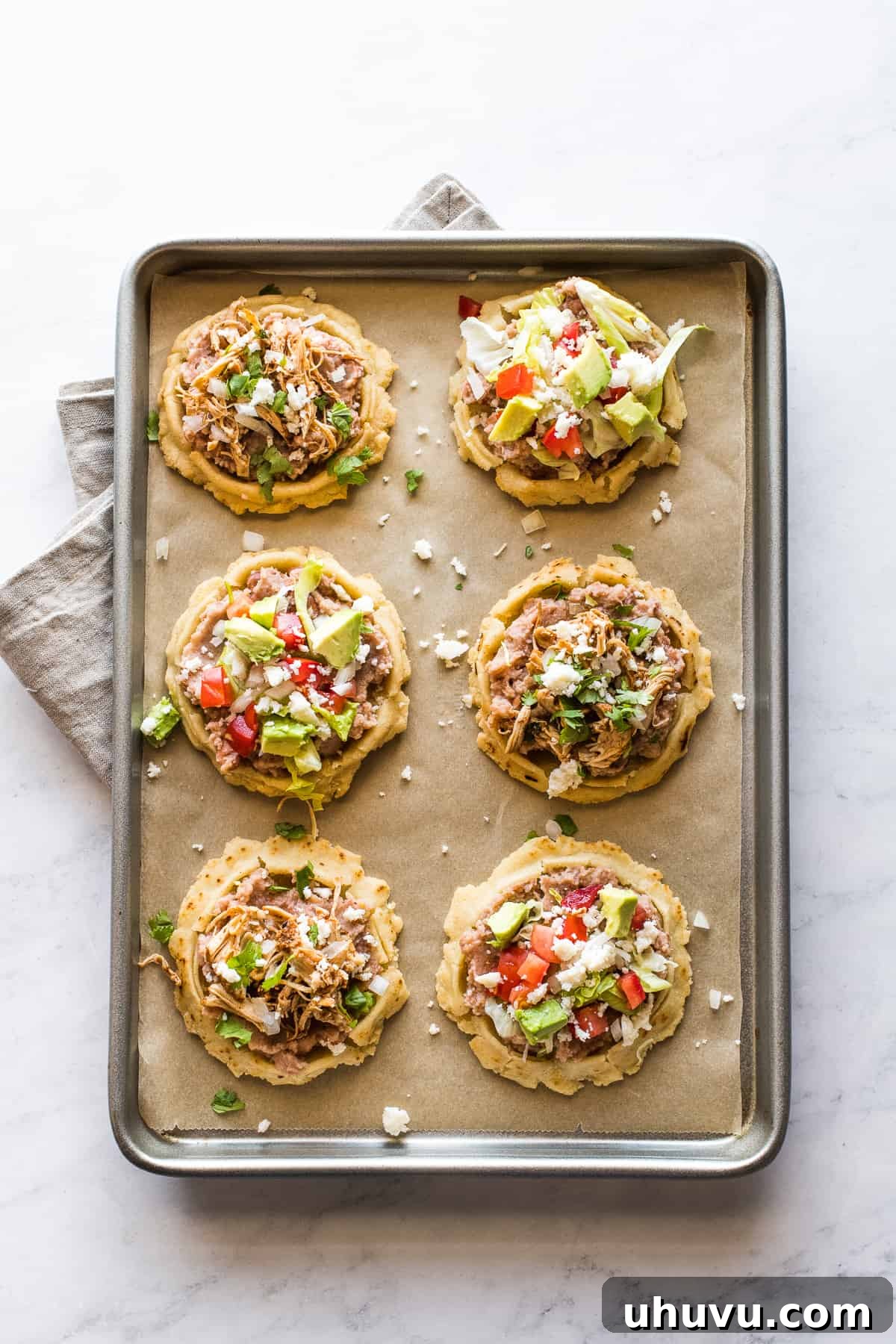 Top 20 Irresistible Mexican Bites for Your Epic Fiesta 10 Authentic Mexican sopes on a sheet pan, topped with various delicious ingredients.