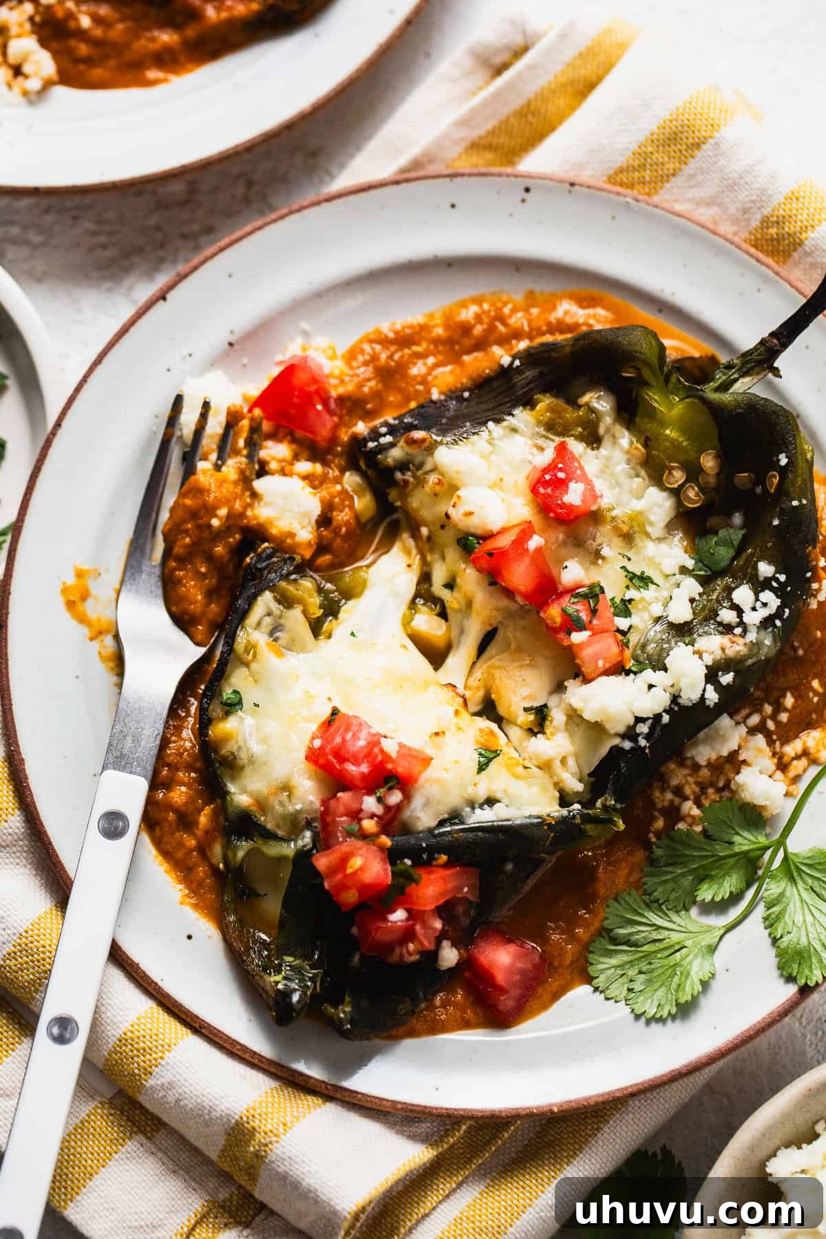 Easy Baked Chile Rellenos 2 Baked chile relleno on a plate with ranchero sauce, garnished with fresh toppings.